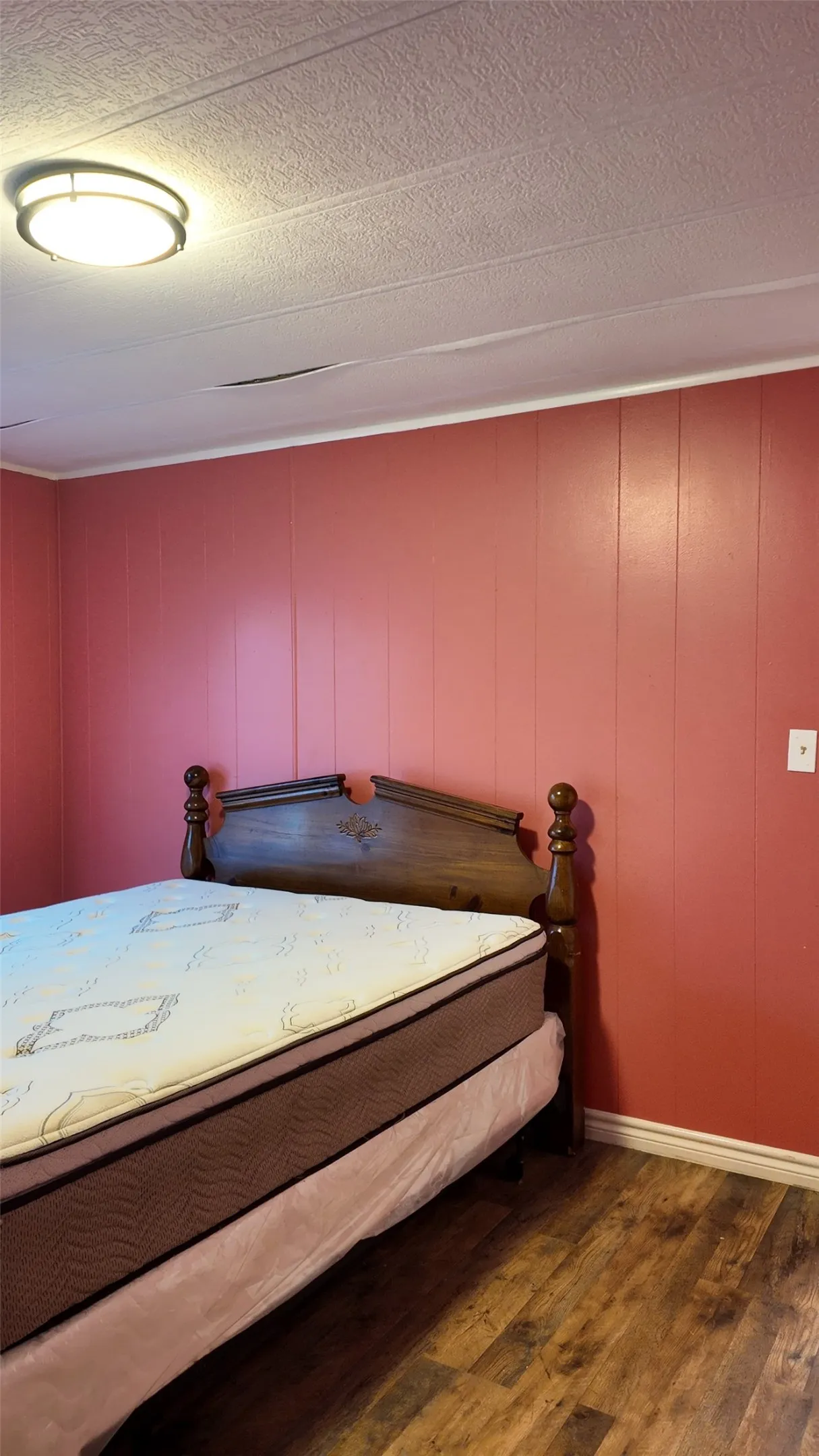 Wood-finish flooring with red paneling walls and a textured ceiling