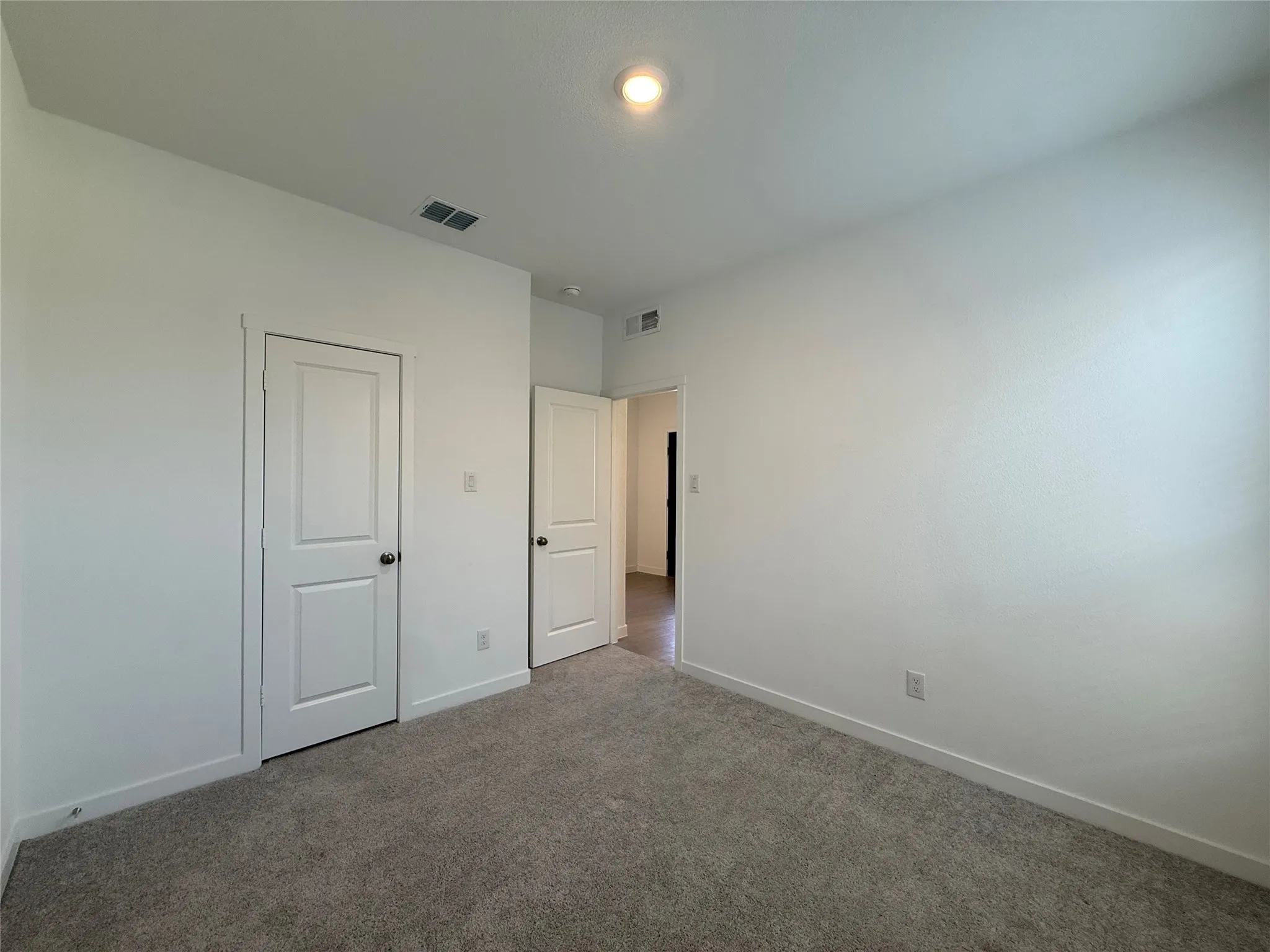 Plush grey carpeting, white interior doors, and a recessed ceiling light