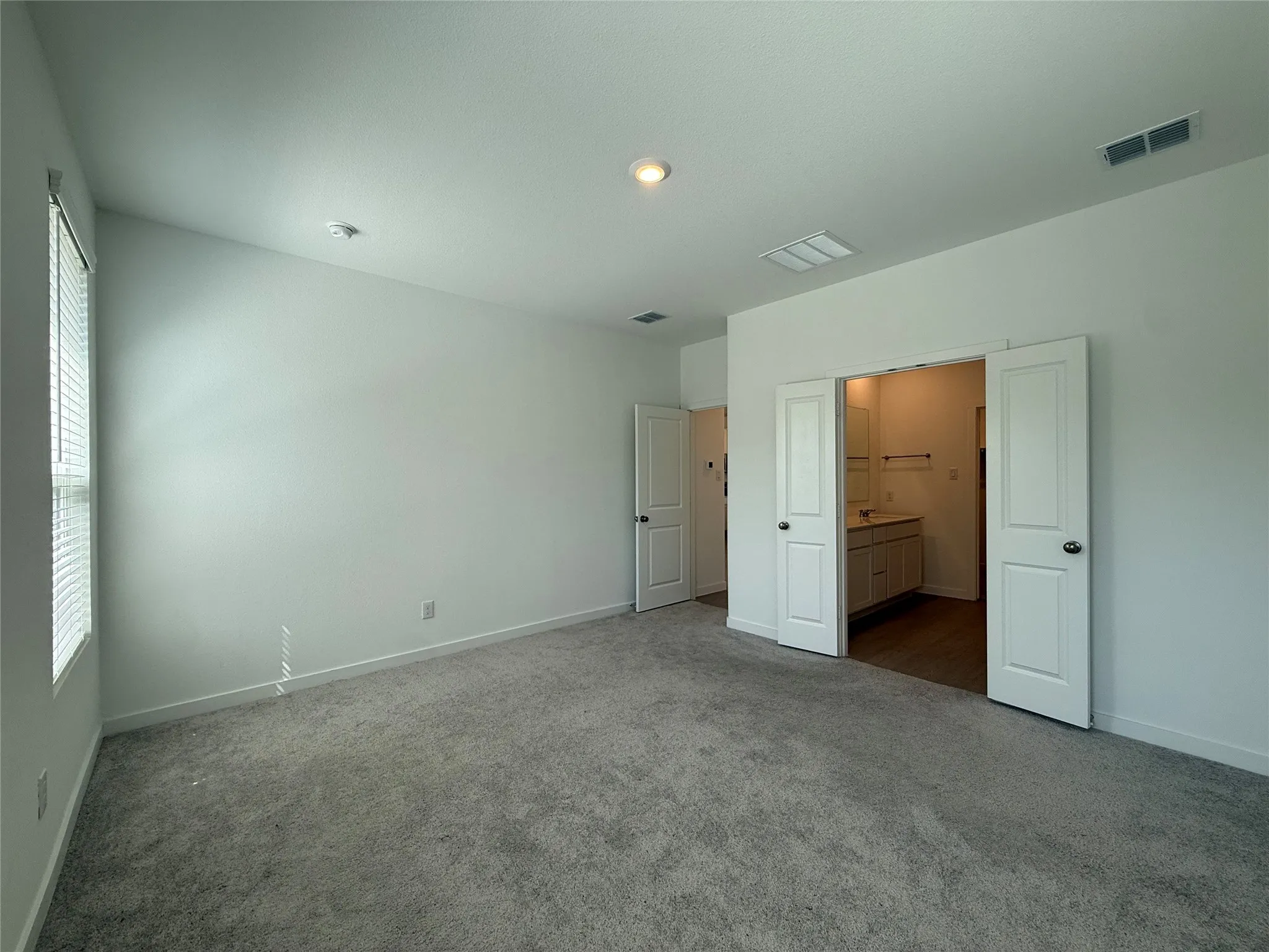 Plush gray carpeting, white walls, and a window with horizontal blinds
