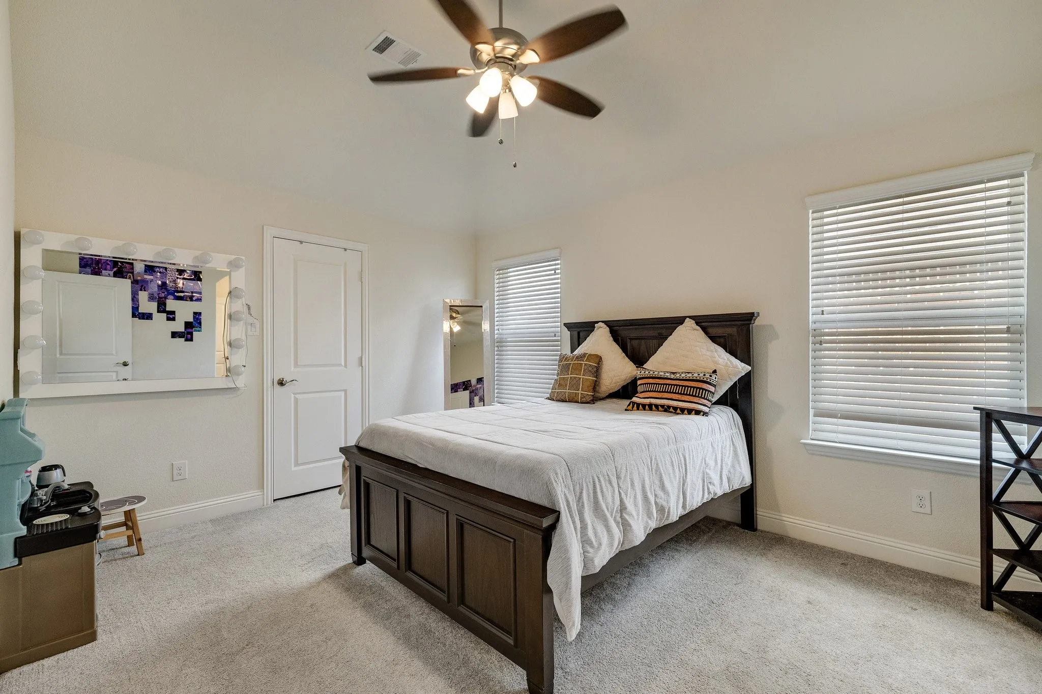Vaulted ceiling, ceiling fan, carpeting, two windows with blinds, and a paneled door