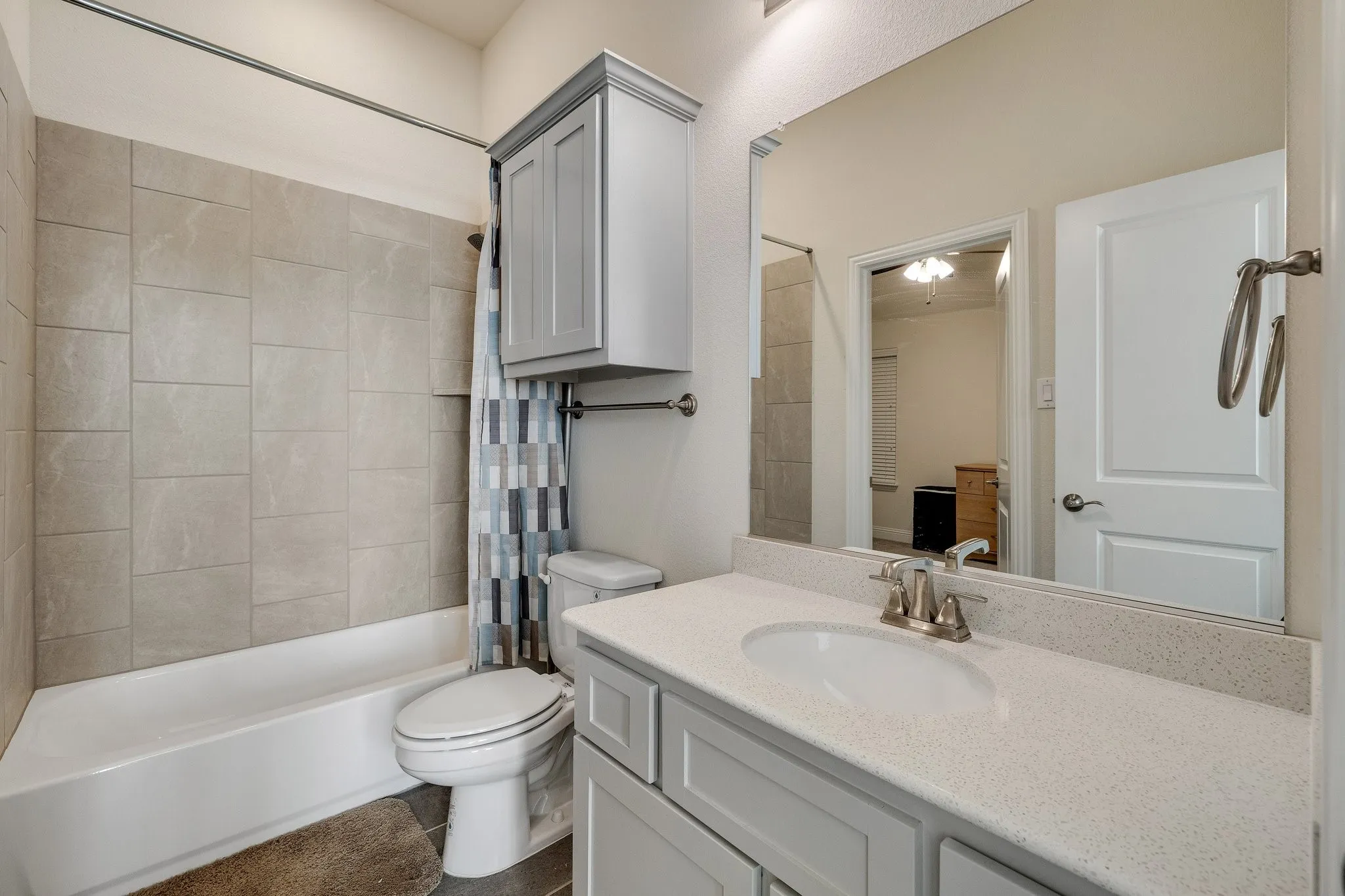 Built-in vanity with light-colored countertop, undermount sink, and brushed nickel faucet