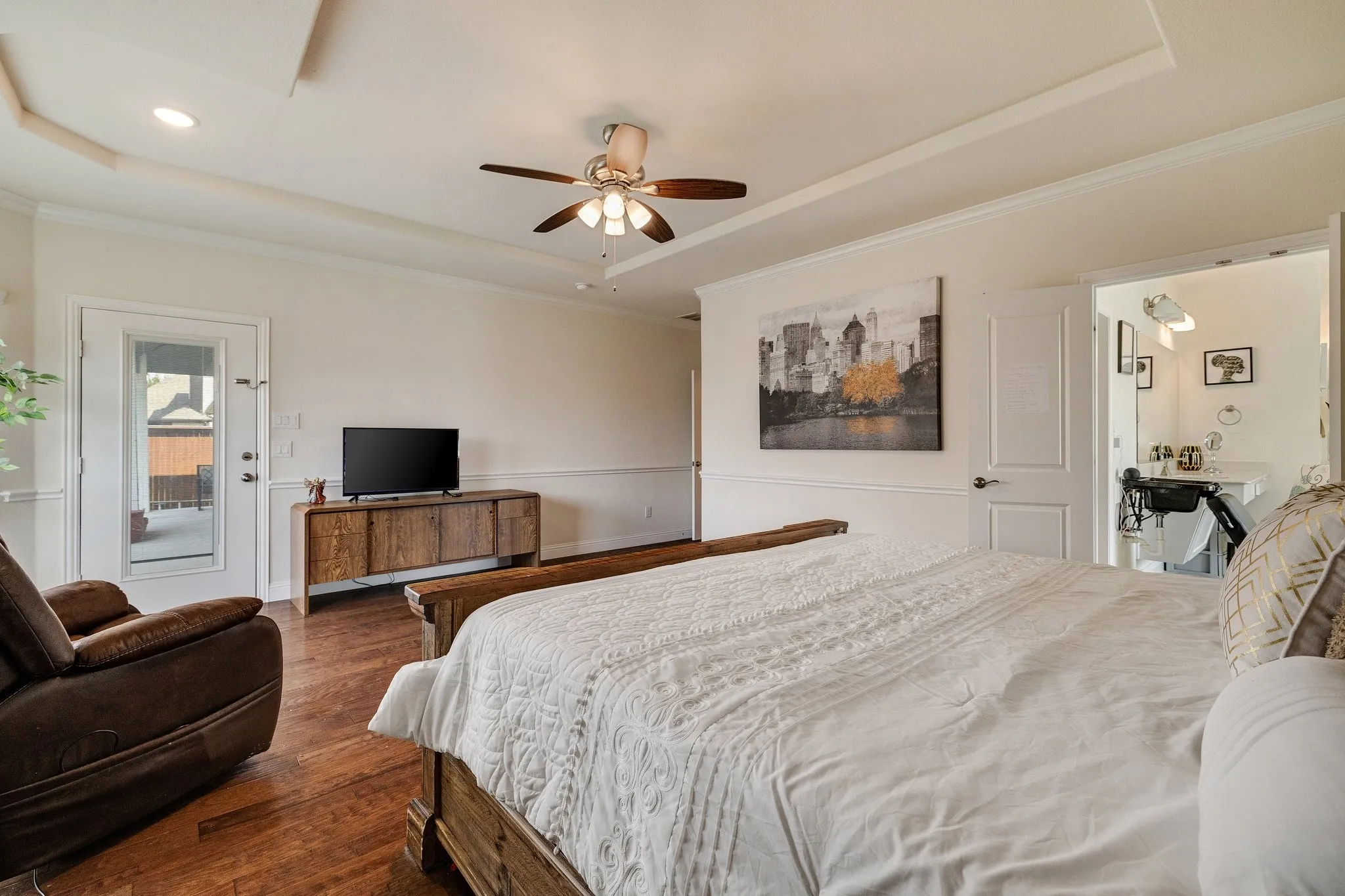 Wood-finish flooring, tray ceiling, recessed lighting, ceiling fan, and access to an outdoor area