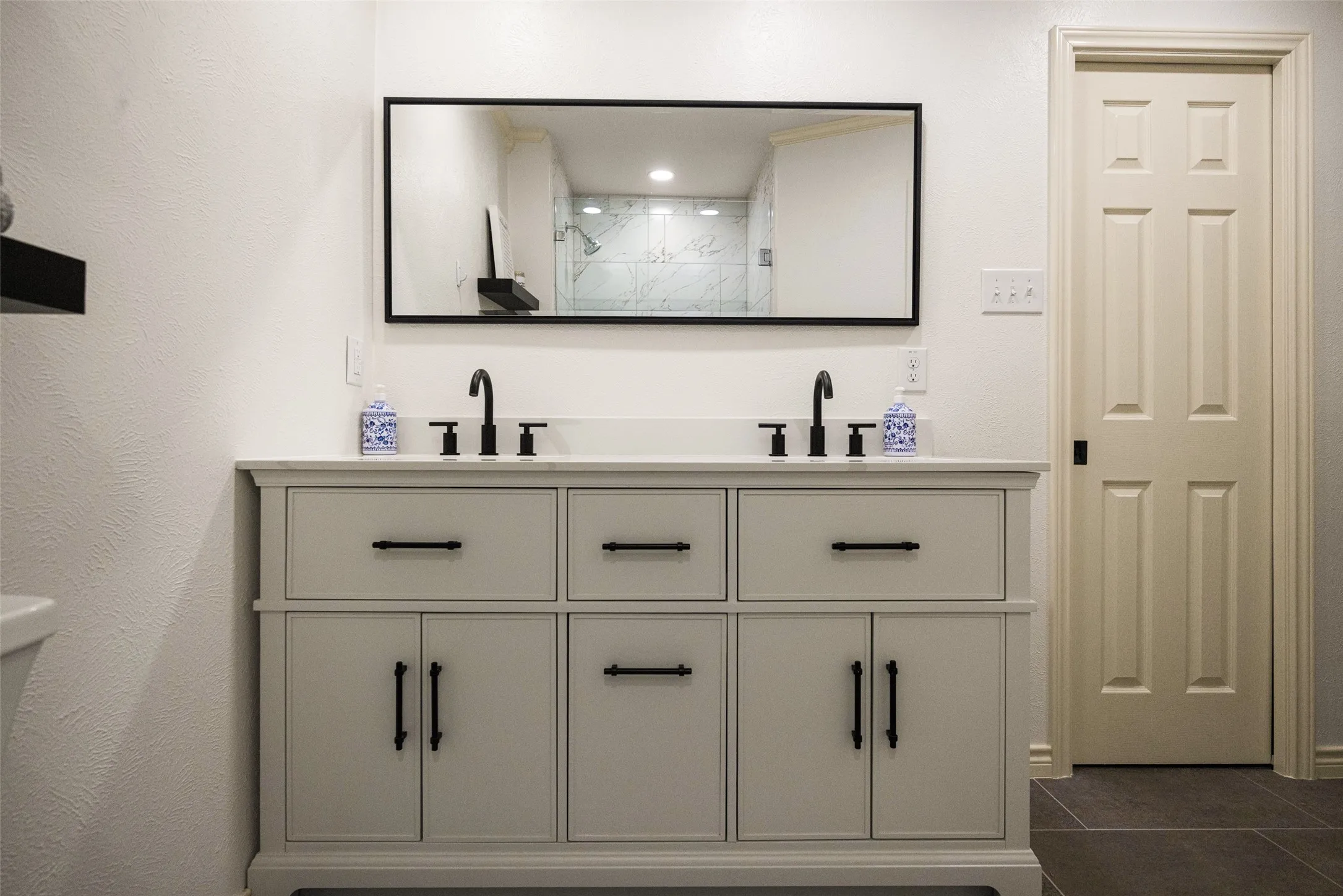 Dual vanity with white countertop, matte black fixtures, and cabinet storage