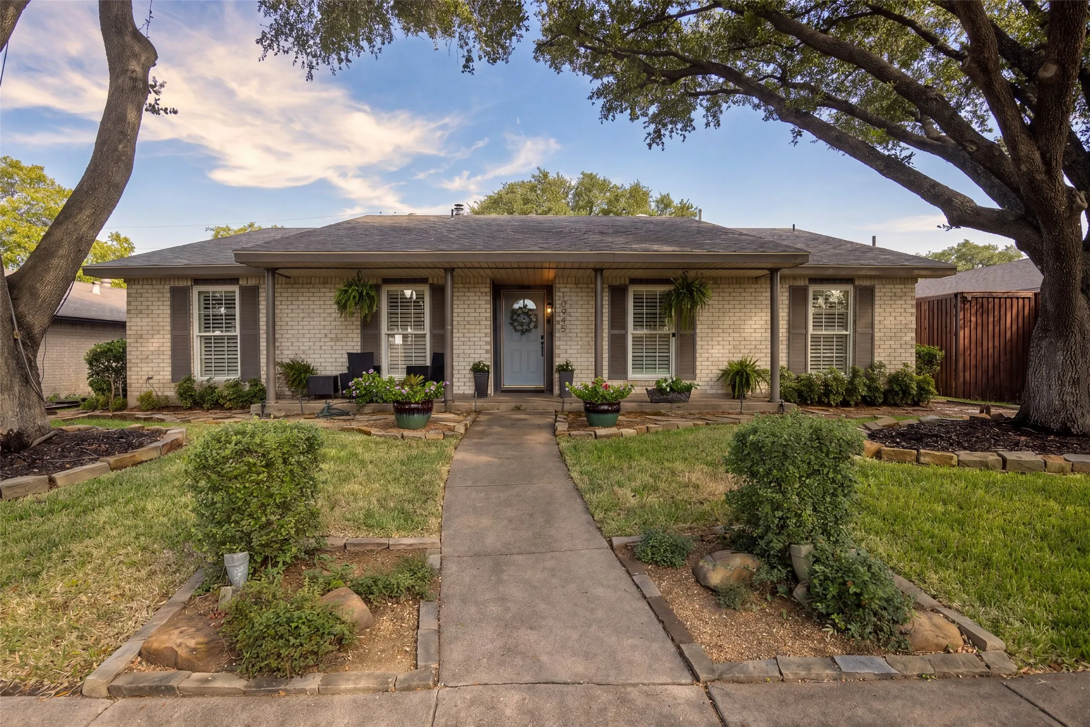 Brick exterior with dark shutters, covered front entry, and a concrete walkway