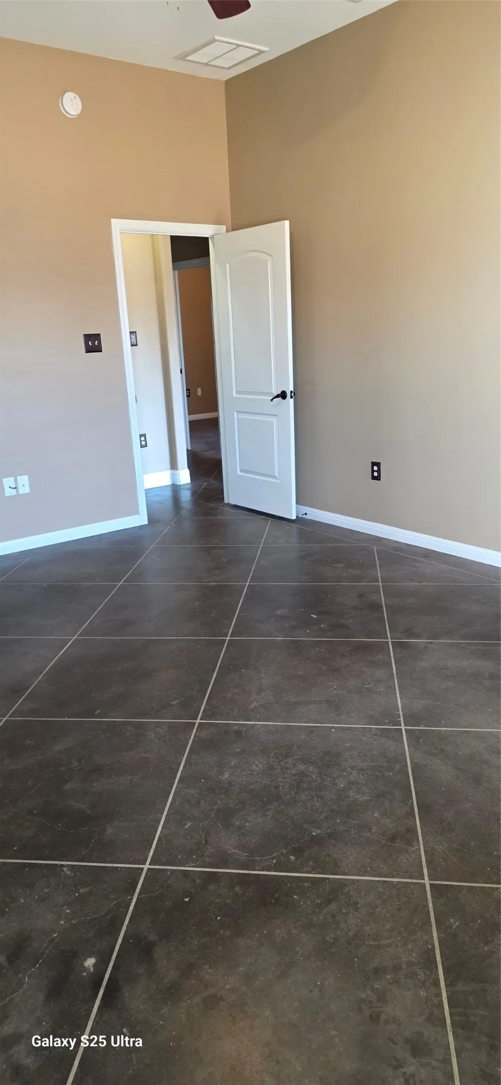 Expansive tile flooring, neutral wall tones, and a ceiling fan
