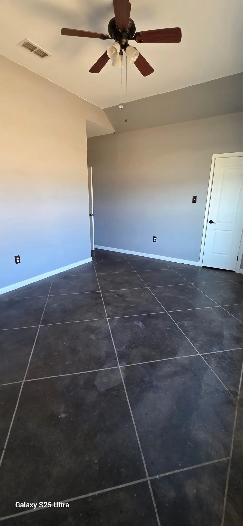 Vaulted ceiling with an attached ceiling fan, tile flooring, and neutral wall tones