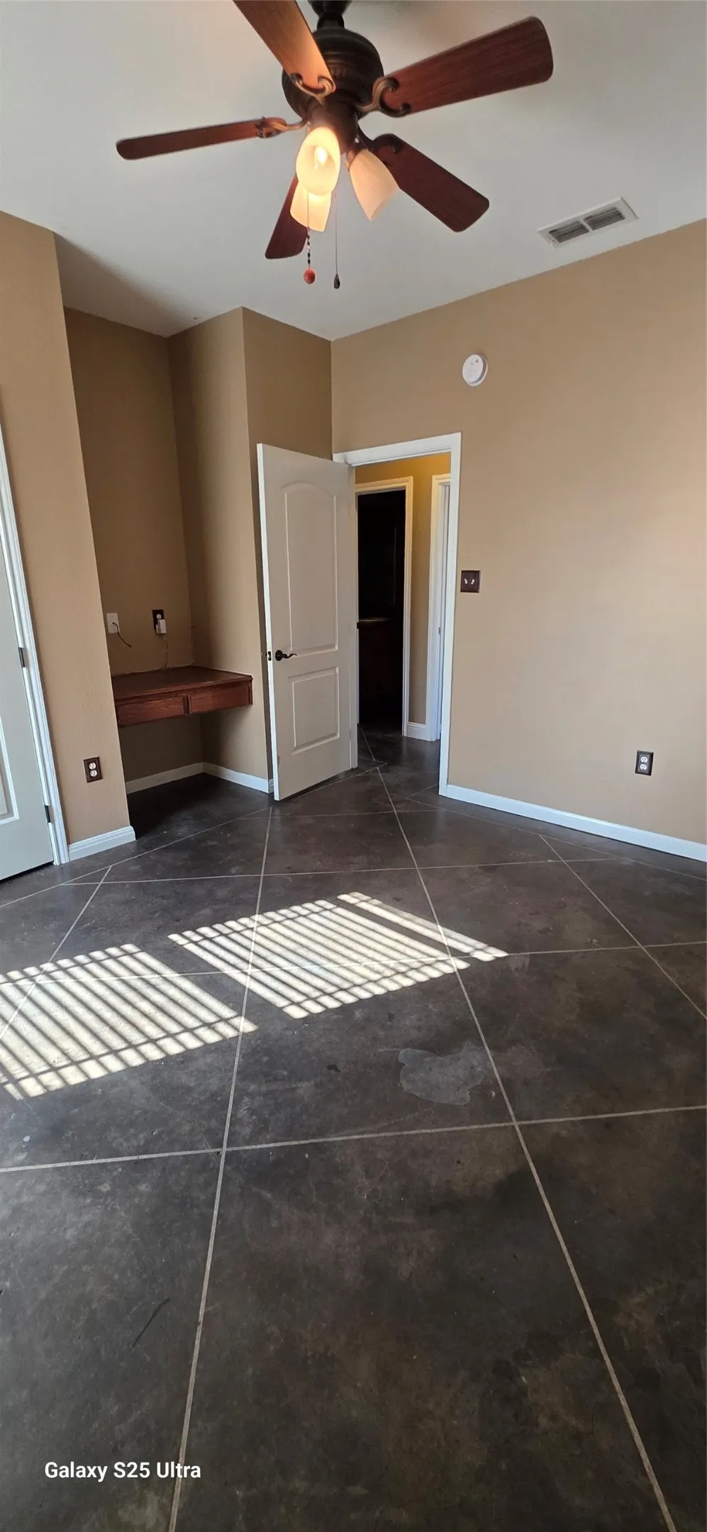 Ceiling fan with integrated lighting, tiled flooring, built-in wooden desk, and neutral wall tones