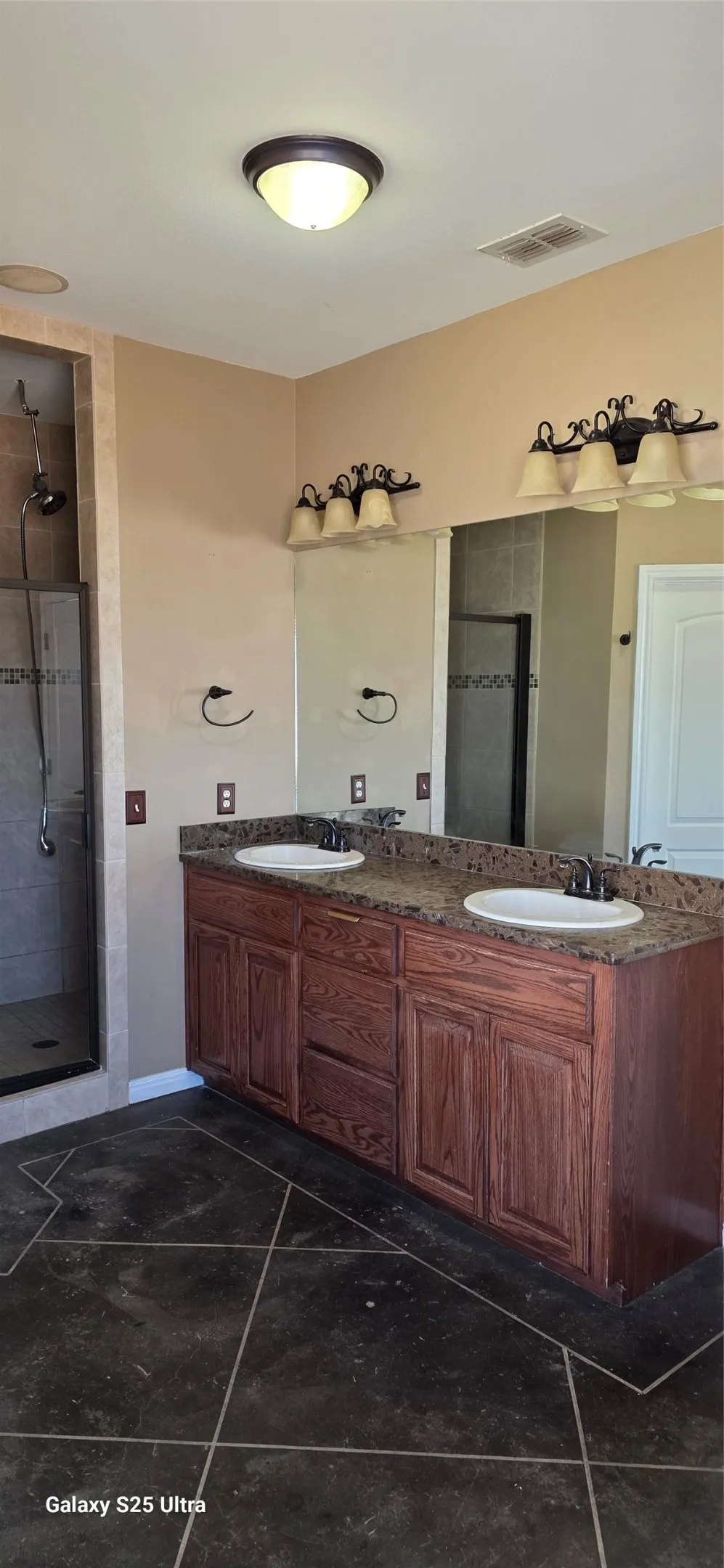 Double vanity with granite-style countertop, dual round sinks, and dark wood-finish cabinetry