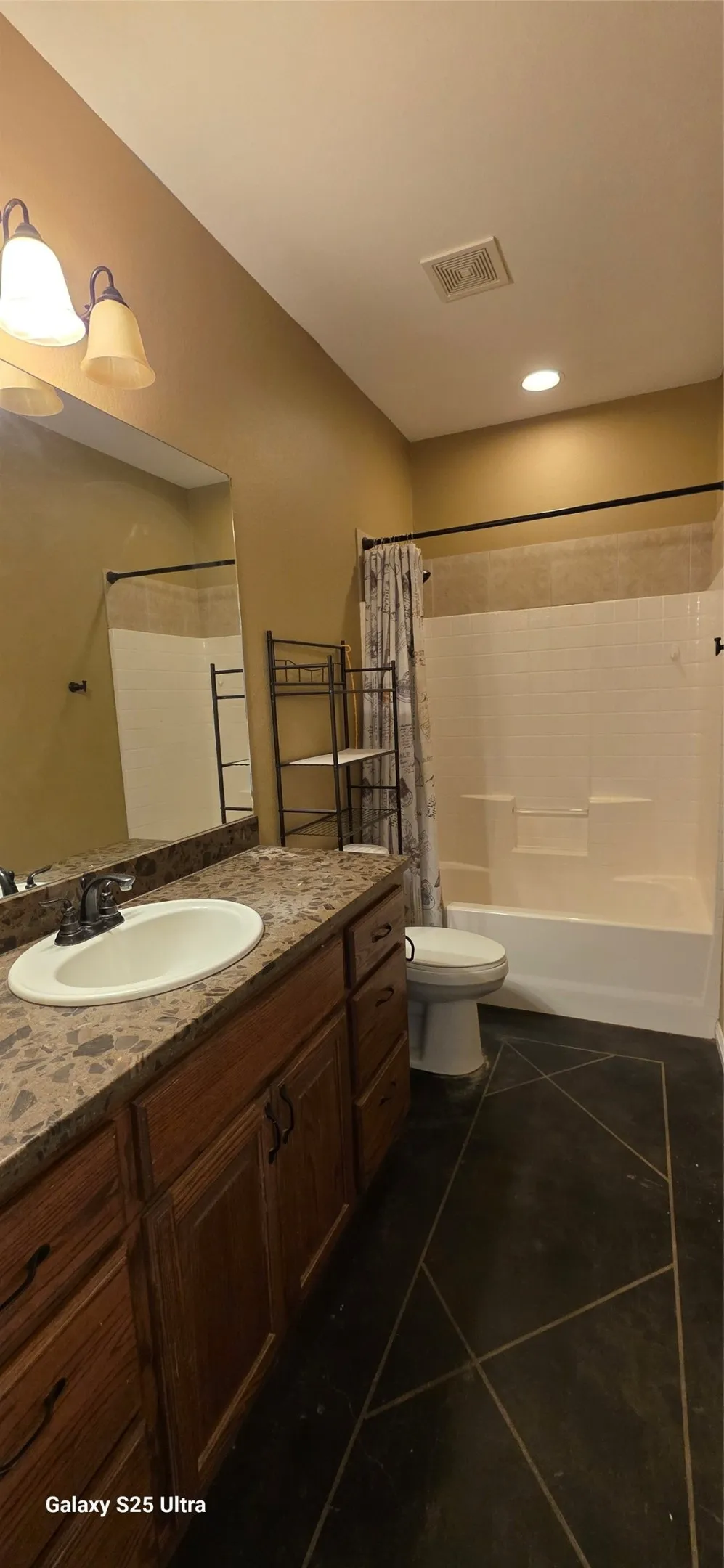 Bathroom featuring an integrated sink, vanity with wood-finish cabinetry, and a shower-tub combination
