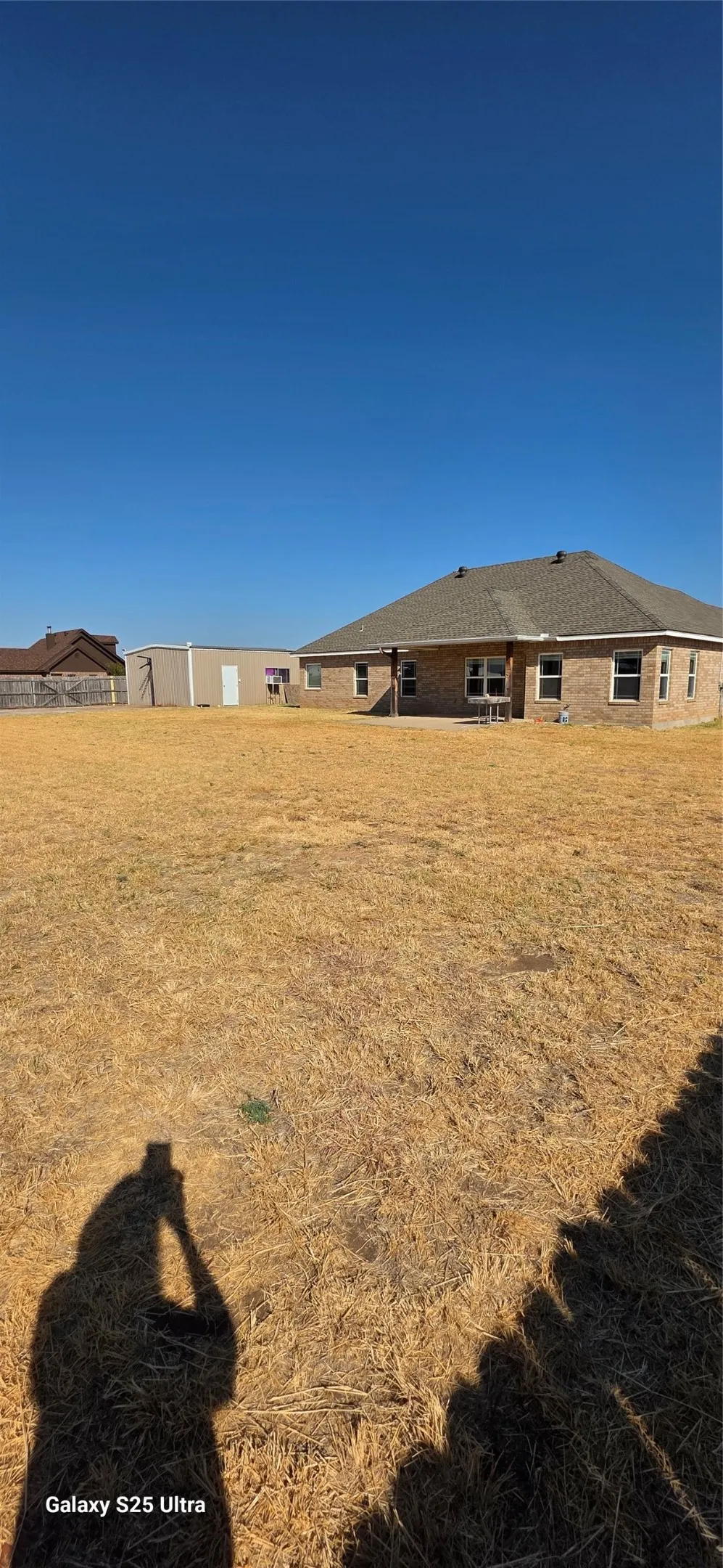 Expansive backyard featuring a large grass area and a detached auxiliary building