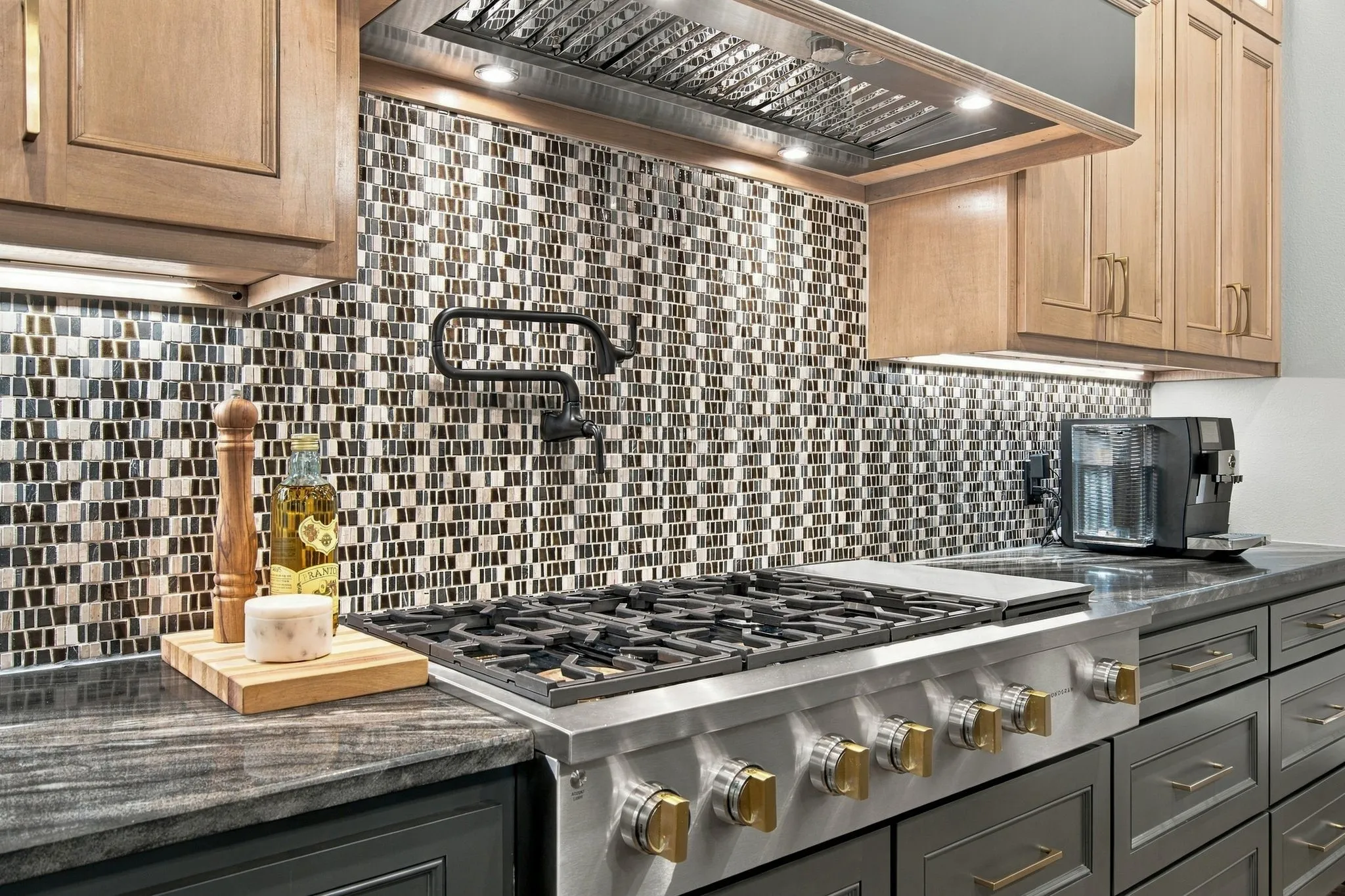 Designed for the serious home chef, the kitchen features a professional-style GE Monogram gas cooktop framed by a dramatic custom vent hood and striking mosaic backsplash. A convenient pot filler, substantial counter space and under-cabinet lighting complete this beautifully appointed cooking station where luxury meets everyday function.