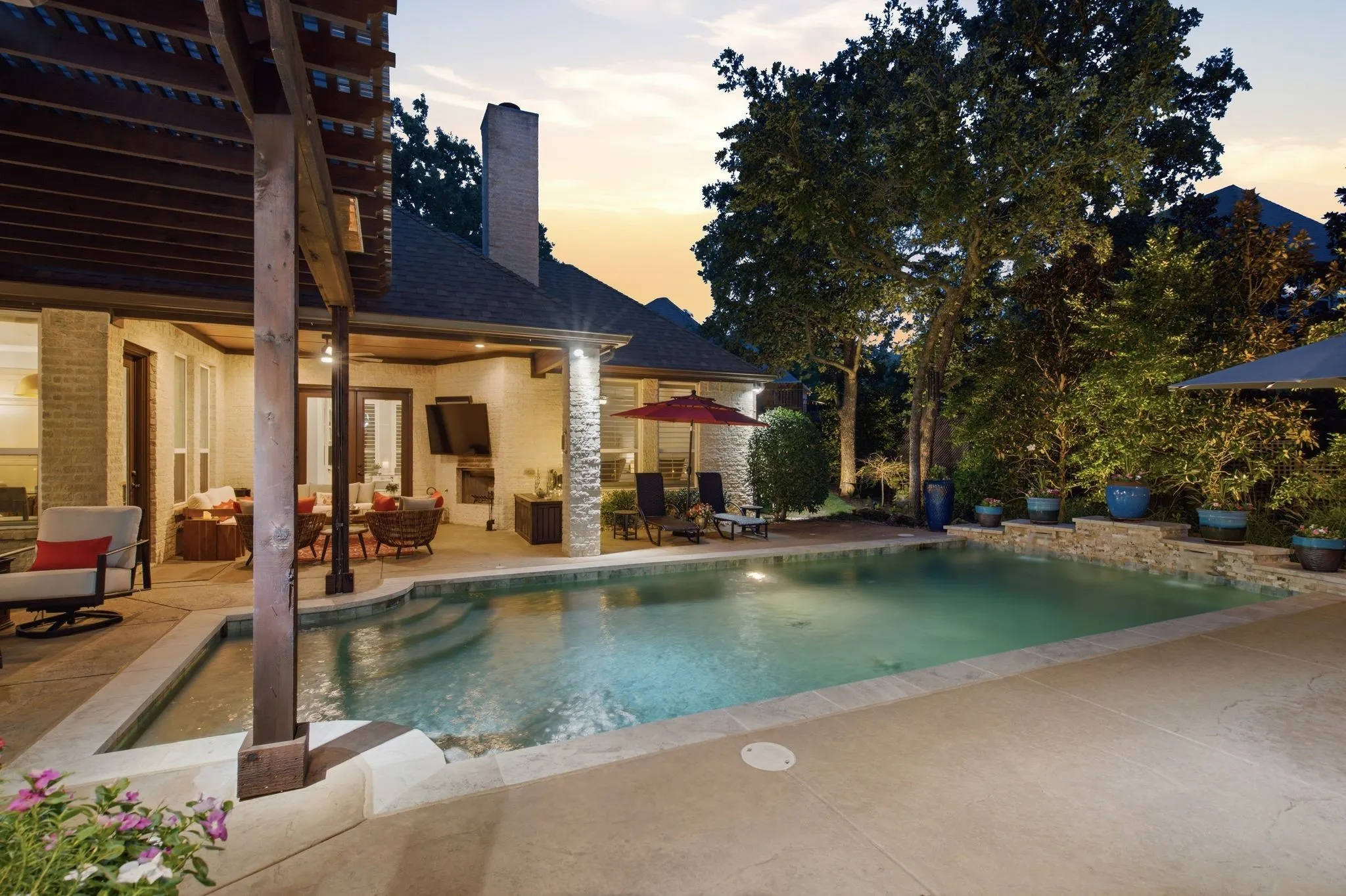 Resort-style living continues with a sparkling pool framed by mature trees, lush landscaping and generous poolside lounging space. An expansive covered patio creates an outdoor living room complete with fireplace and TV, offering a comfortable setting for year-round entertaining, quiet evenings by the fire or relaxed summer days beside the pool.