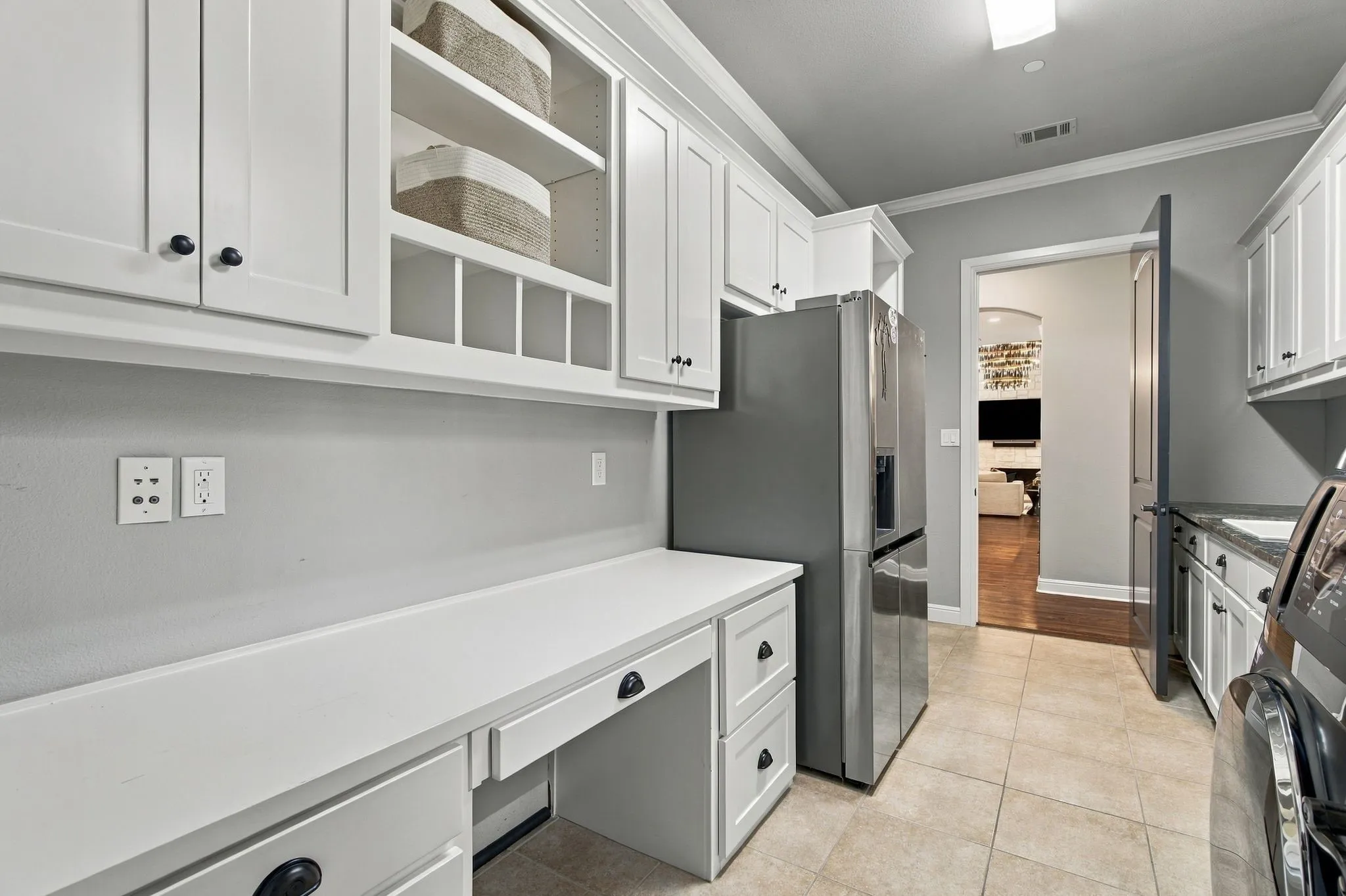 Generously sized utility room designed to make everyday tasks easier, with extensive built-in cabinetry, abundant counter space and a dedicated work or folding station. Space for a full-size washer and dryer plus an additional refrigerator adds exceptional storage and functionality to this thoughtfully designed room.
