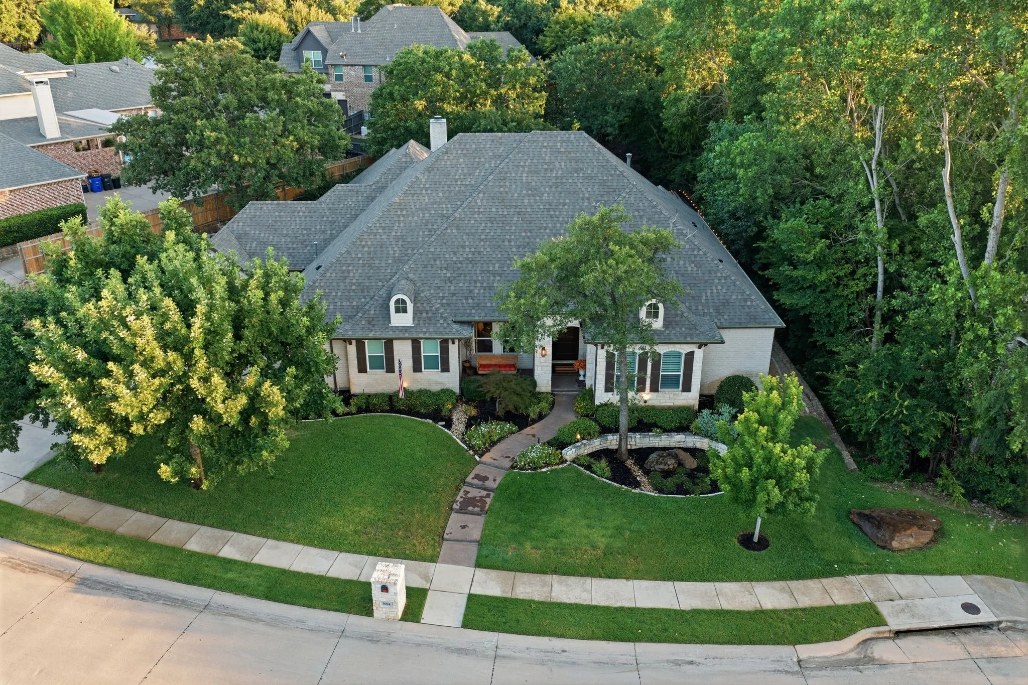 Beautiful traditional home with timeless French Country influences, featuring an elegant brick exterior, charming dormer windows and a stately roofline. Mature trees, lush landscaping and a manicured lawn create wonderful curb appeal and a warm, inviting first impression.