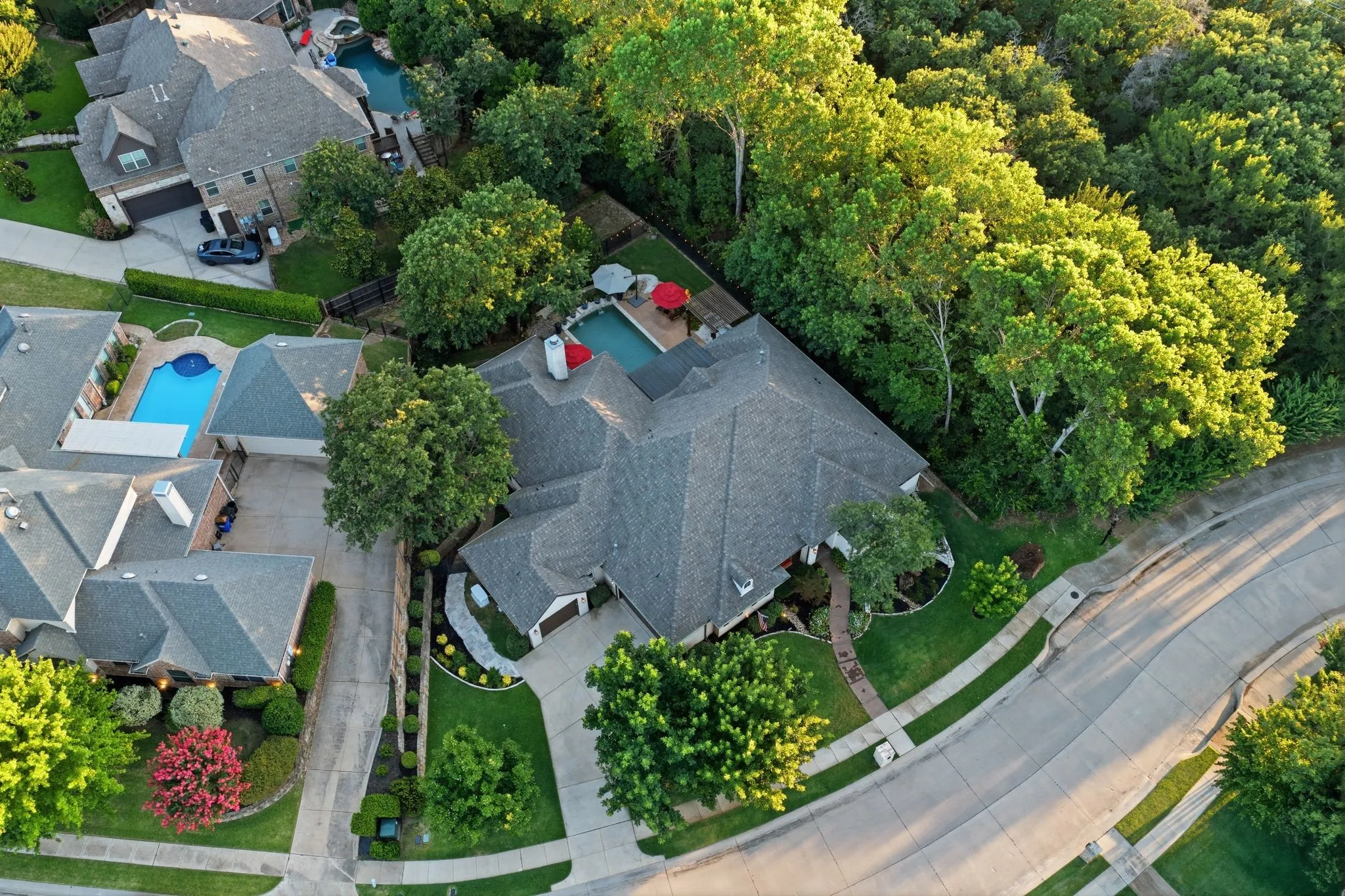 Gabled roofline residence featuring a private pool area, extensive landscaping, and a curvilinear driveway.