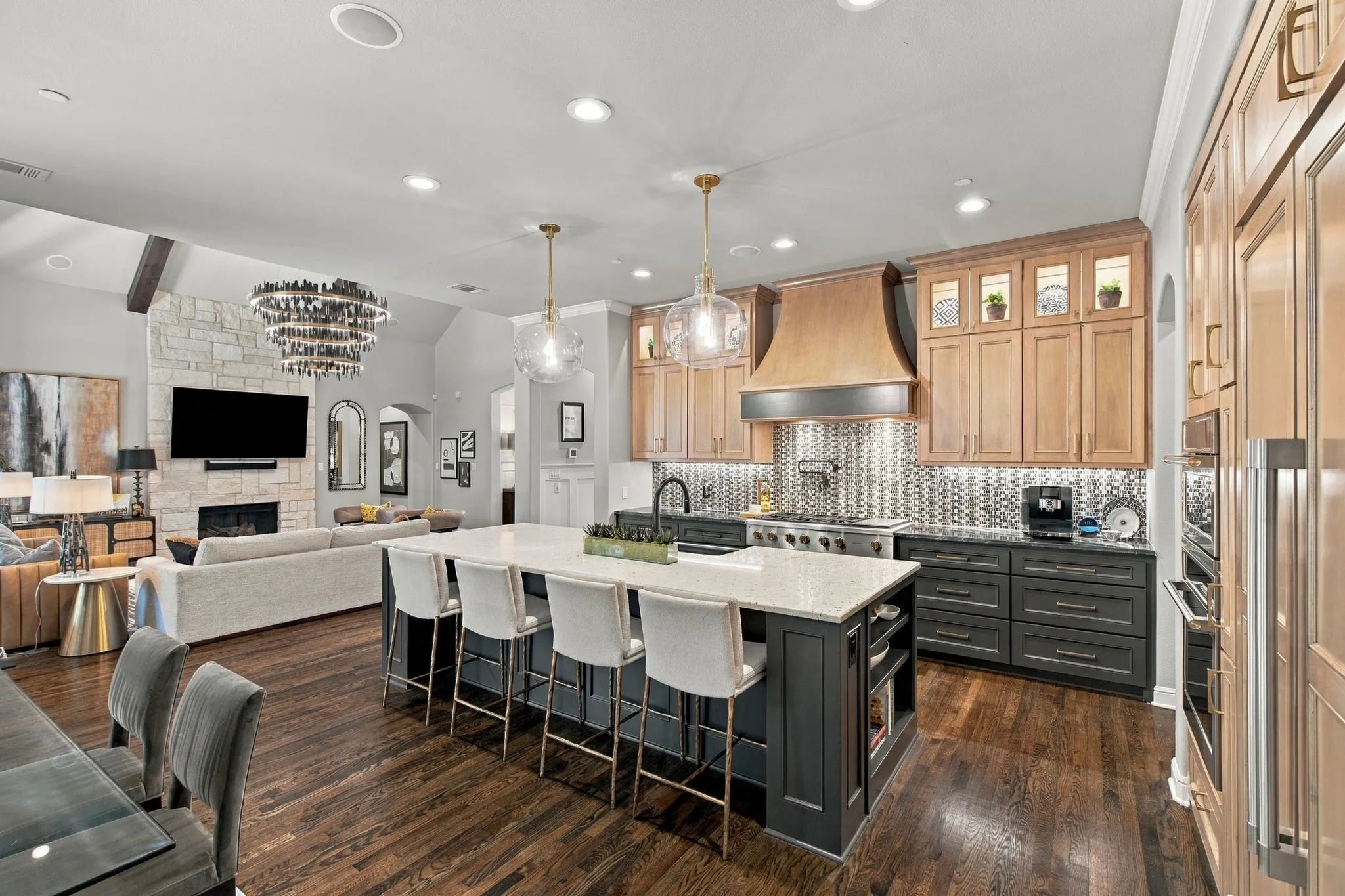 Showstopping chef’s kitchen designed to impress, anchored by an oversized island with generous seating and dramatic designer pendants. A striking custom range hood, extensive cabinetry, statement backsplash and professional-style appliances elevate the space, while rich hardwood floors flow seamlessly into the soaring great room beyond. Sophisticated, spacious and beautifully connected—this is truly the heart of the home.