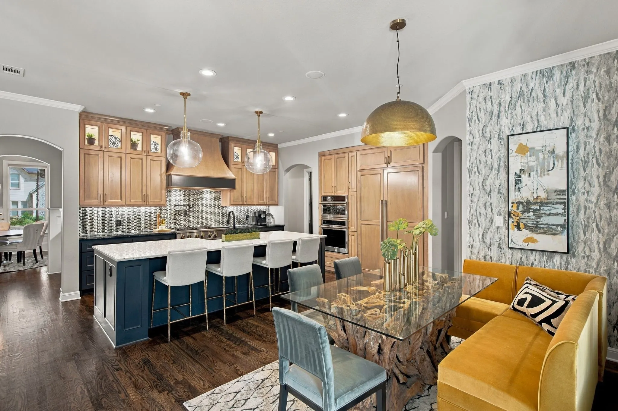 Style and function come together in this beautifully designed kitchen and casual dining space. The oversized island invites conversation and gathering, while the adjoining dining area offers a distinctive setting for everyday meals. Rich hardwood floors, statement lighting, custom cabinetry and curated designer finishes give the entire space a sophisticated personality while maintaining a comfor