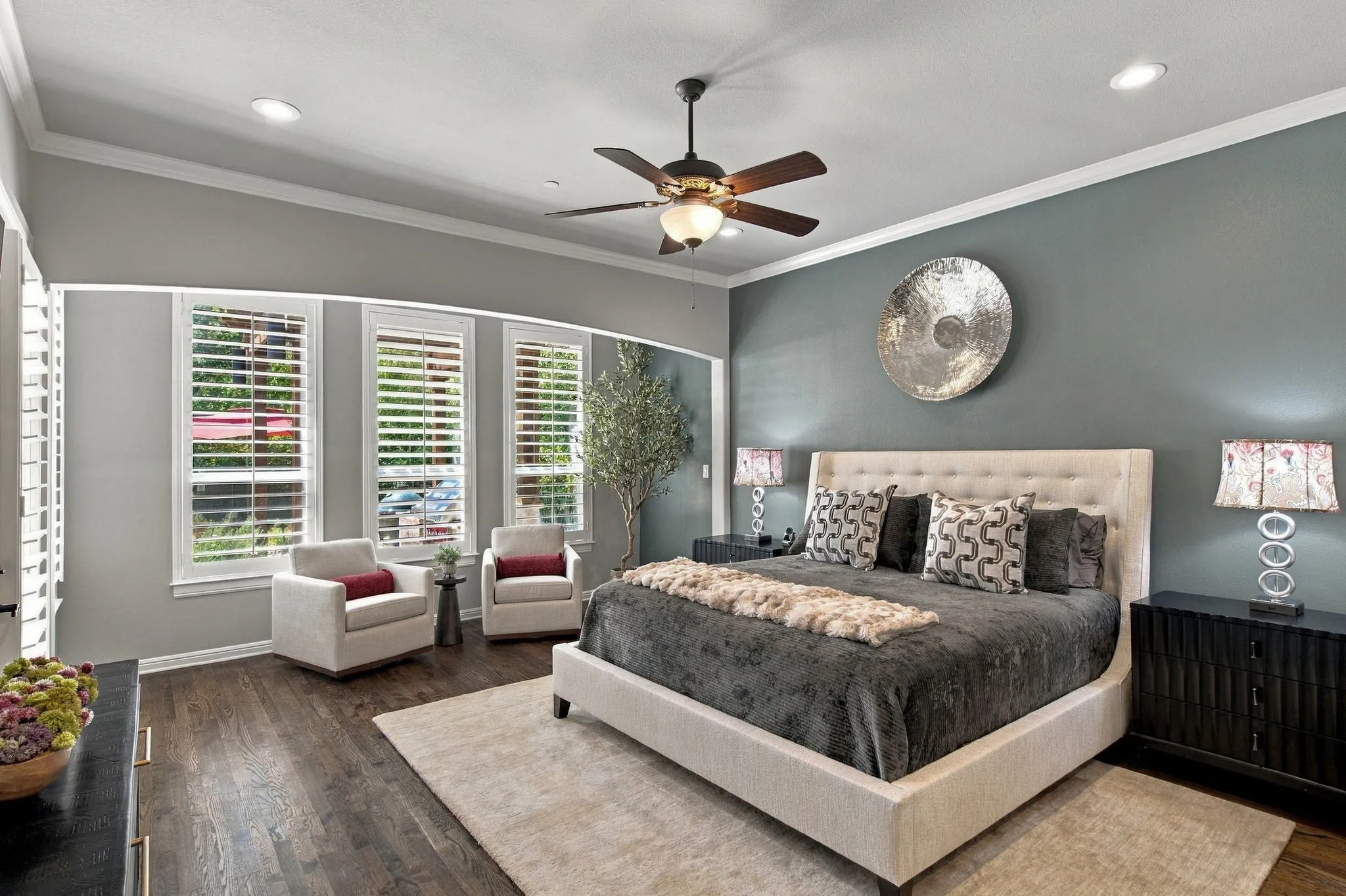Looking for a calm & luxurious Primary Bedroom? A serene and spacious primary suite designed as a private retreat, featuring rich hardwood floors, a tray ceiling and an inviting sitting area surrounded by windows. Abundant natural light, plantation shutters and generous proportions create a sophisticated yet comfortable space to begin and end the day.