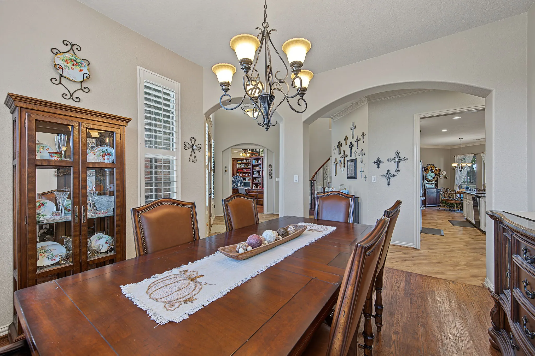 Vaulted ceiling with an iron chandelier, arched entryways, and wood-finish flooring