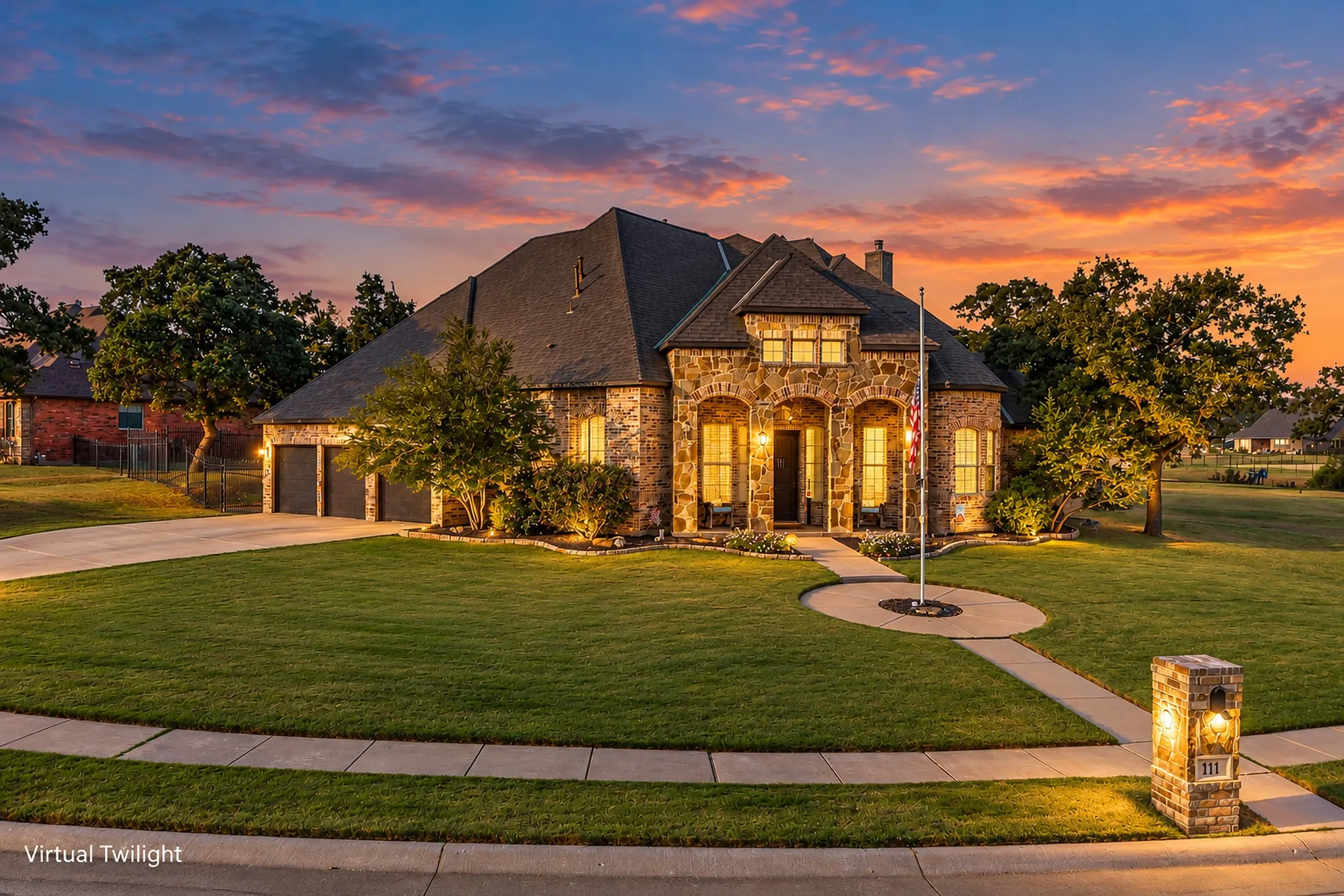 Virtually staged twilight. Stone facade with arched entries, a multi-car garage, and a circular walkway