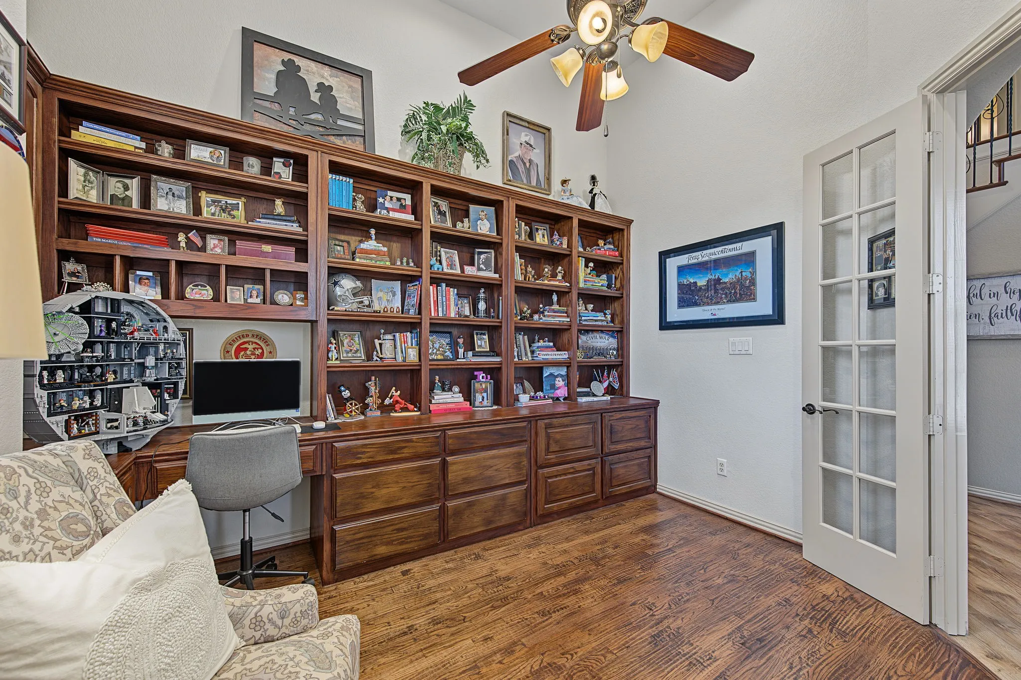 Custom built-in wood cabinetry, wood-finish flooring, vaulted ceiling, ceiling fan with integrated lighting, and French doors