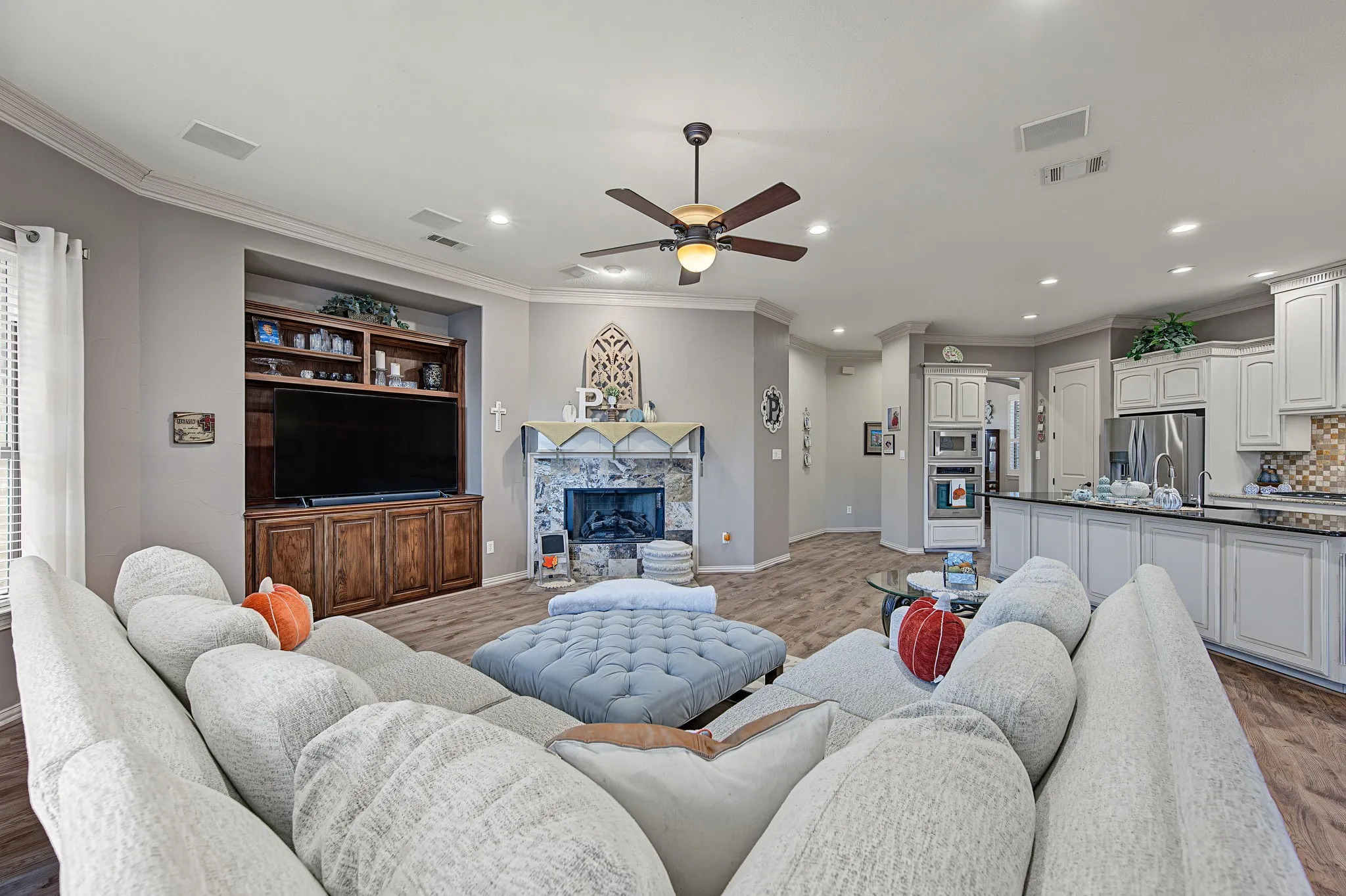 Open-concept living space featuring wood-finish flooring, a built-in media center, and a stone-clad fireplace