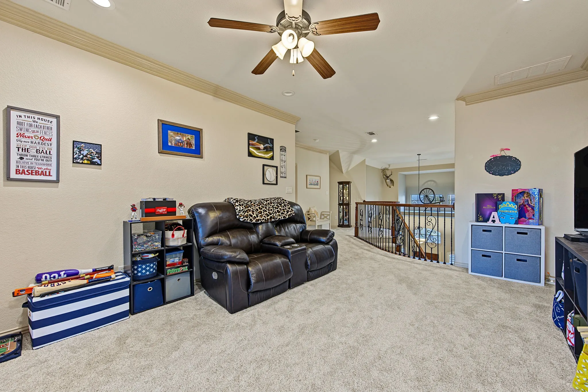 Carpeted secondary living space featuring a ceiling fan with light kit, recessed lighting, and a wrought iron banister overlooking a lower level