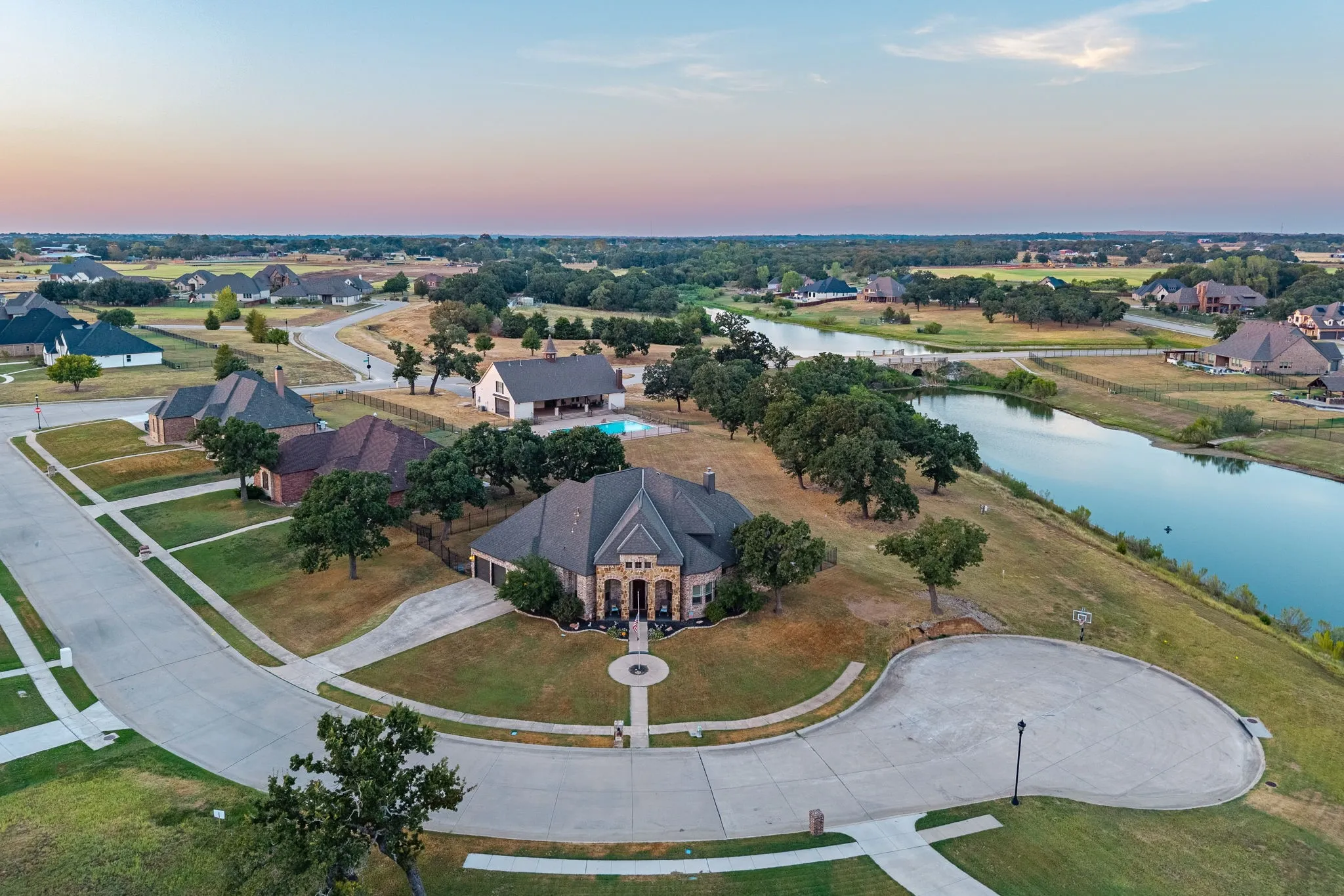 Cul-de-sac residence with a stone and brick exterior, an attached 3 garage, and mature trees