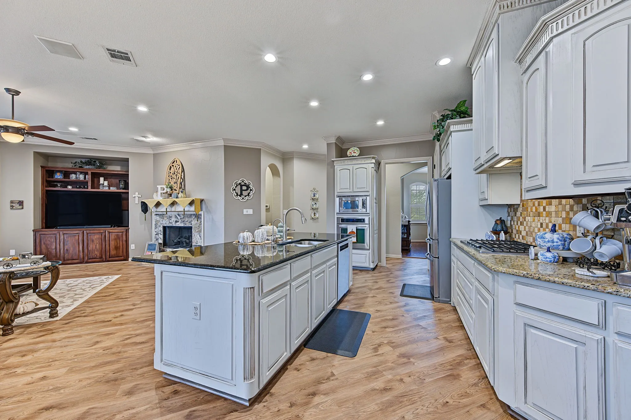 Kitchen island with dark countertop, built-in appliances, and wood-finish flooring