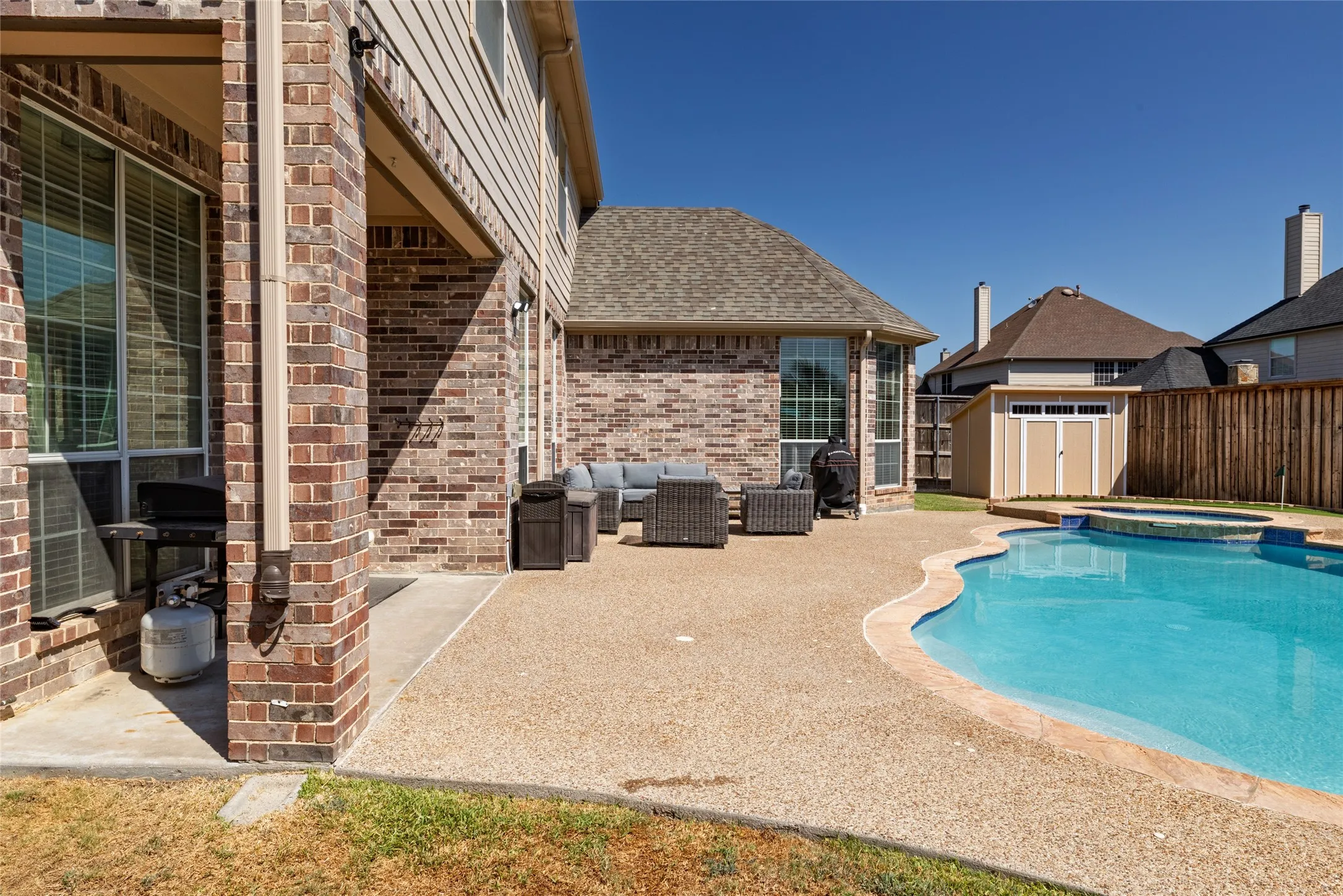 View of covered patio, pool, spa, and shed