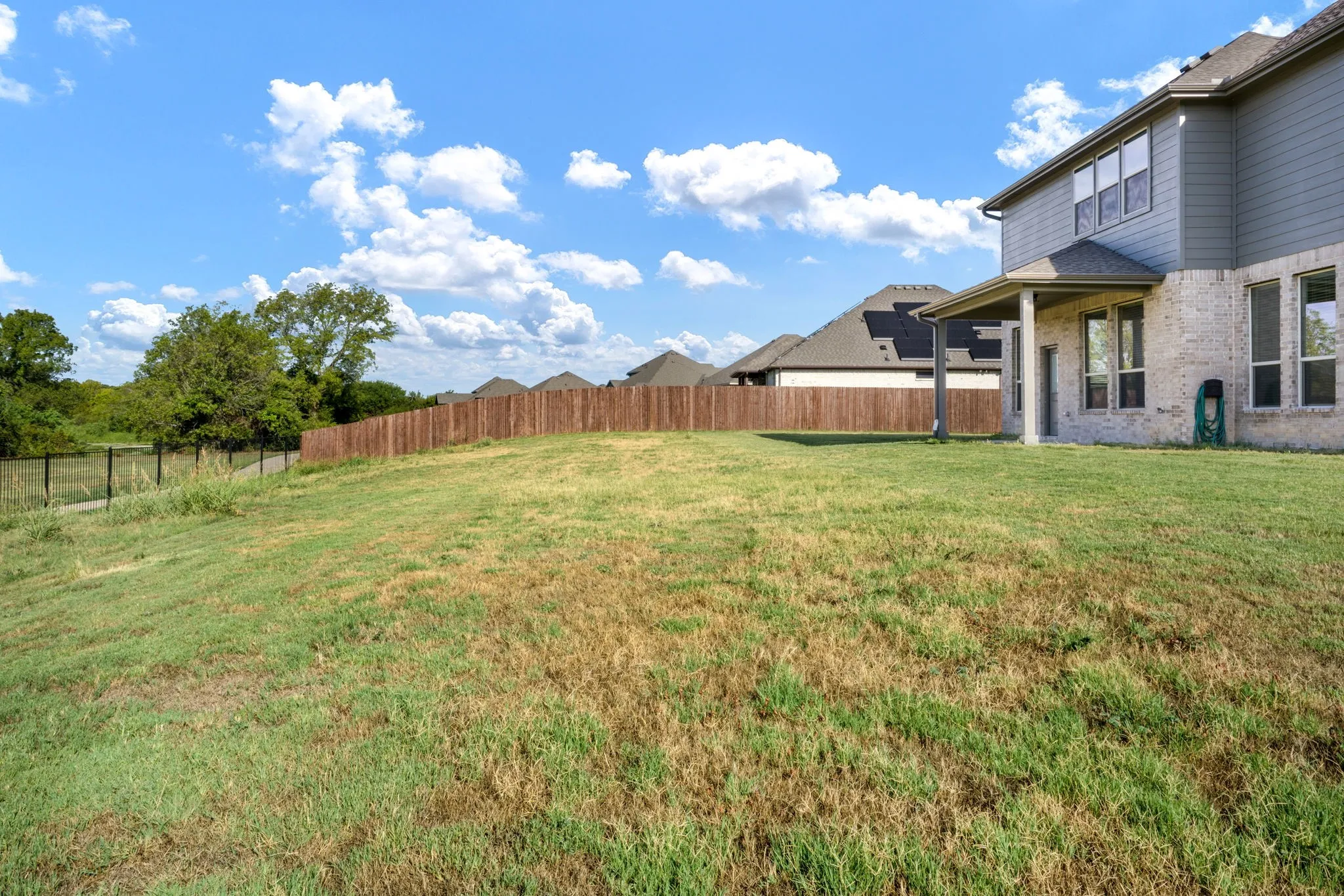 Expansive backyard with a wood privacy fence and a rear patio