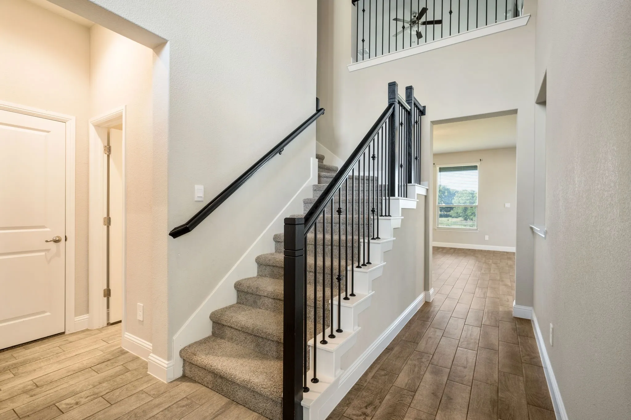 Staircase with carpeted treads and wrought iron balusters