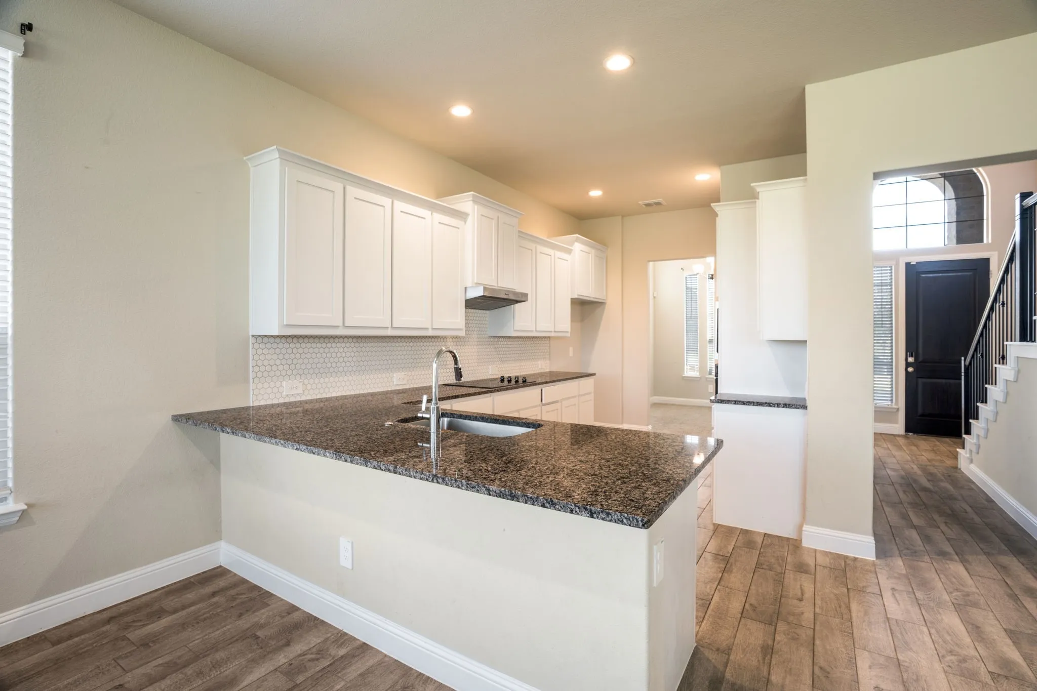 Kitchen featuring white cabinetry, dark granite countertops, and a hexagon tile backsplash