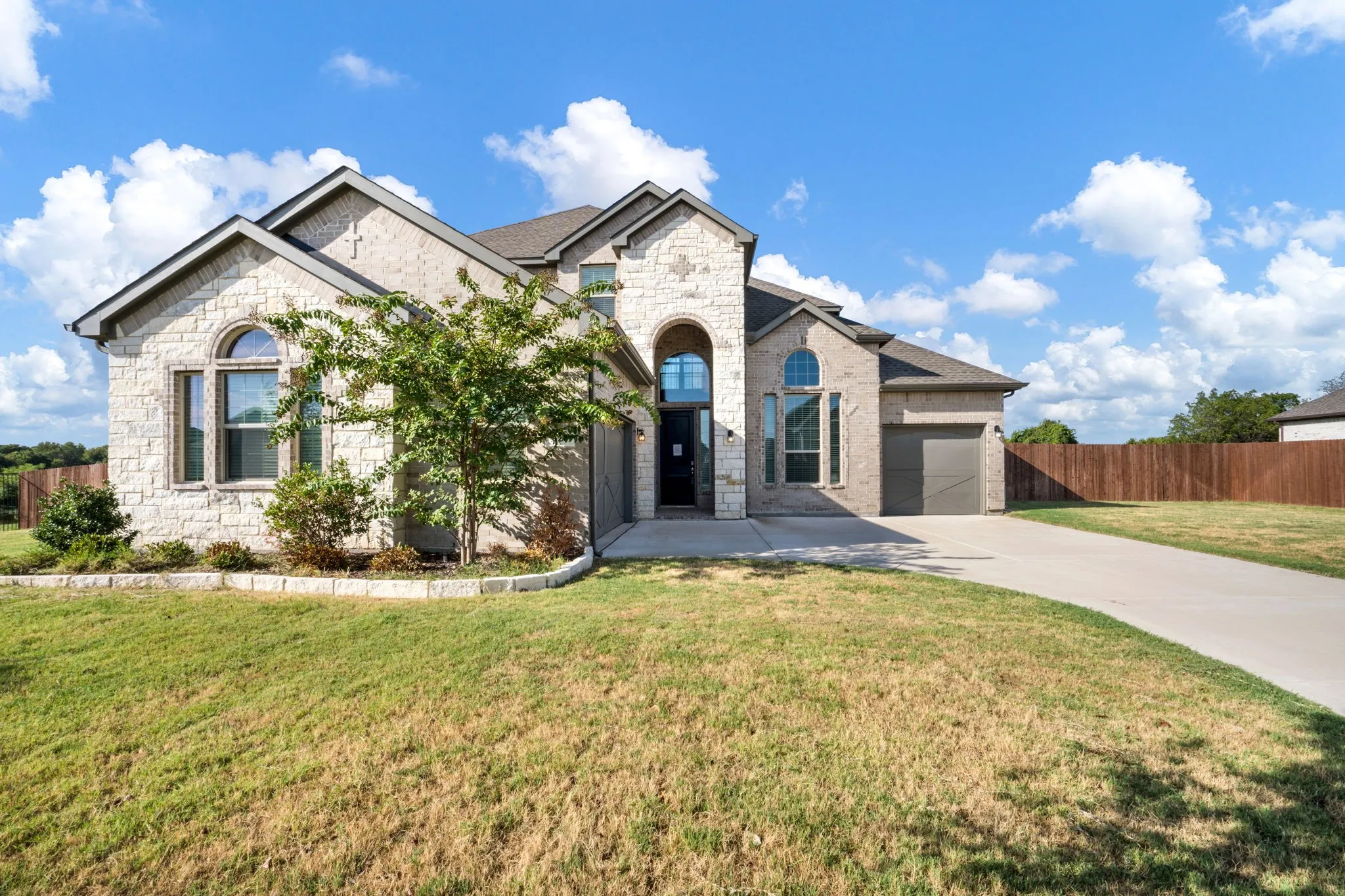 Stone veneer exterior with an arched entryway and two-car garage
