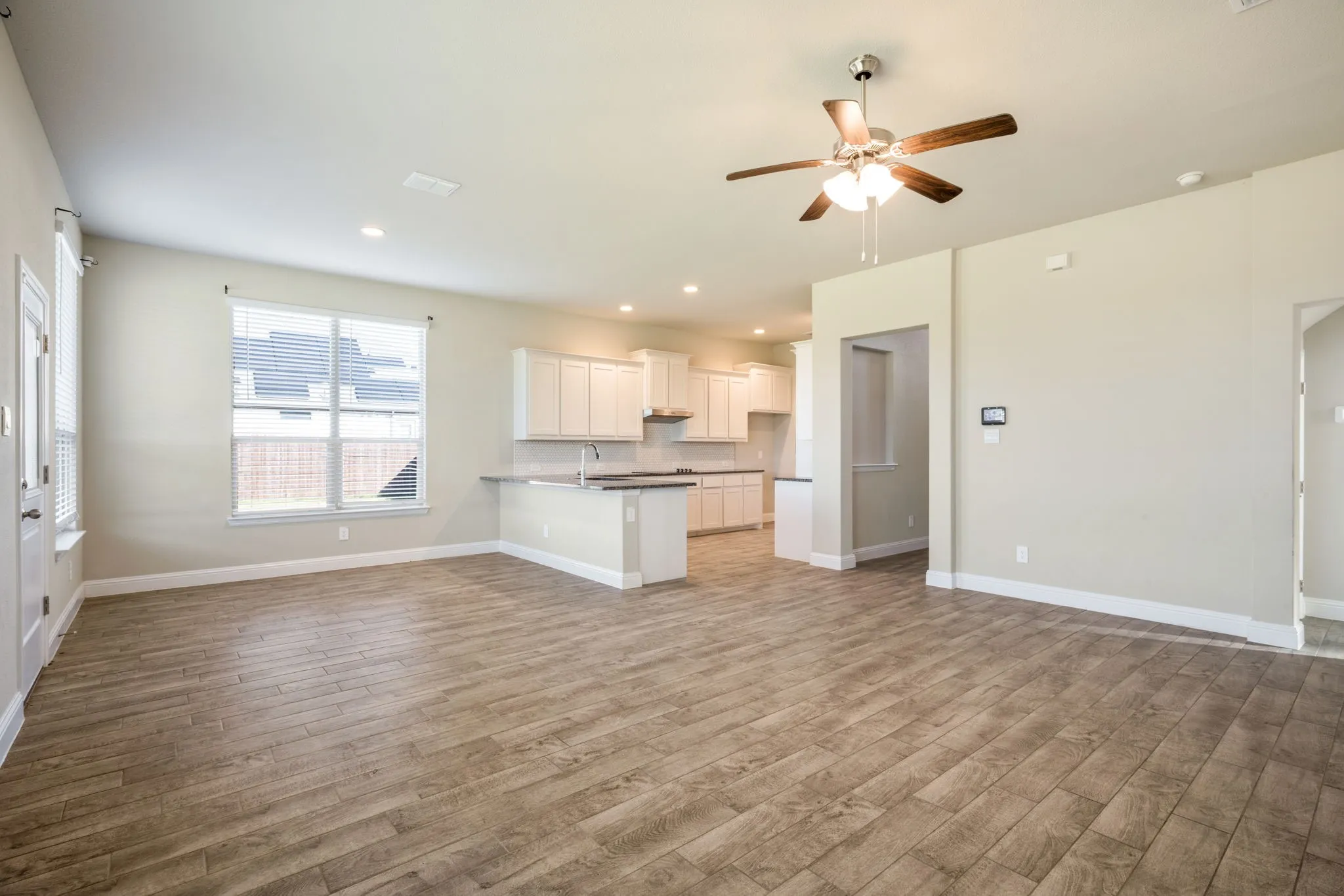 Expansive living area featuring wood-look tile flooring, recessed lighting, and a ceiling fan