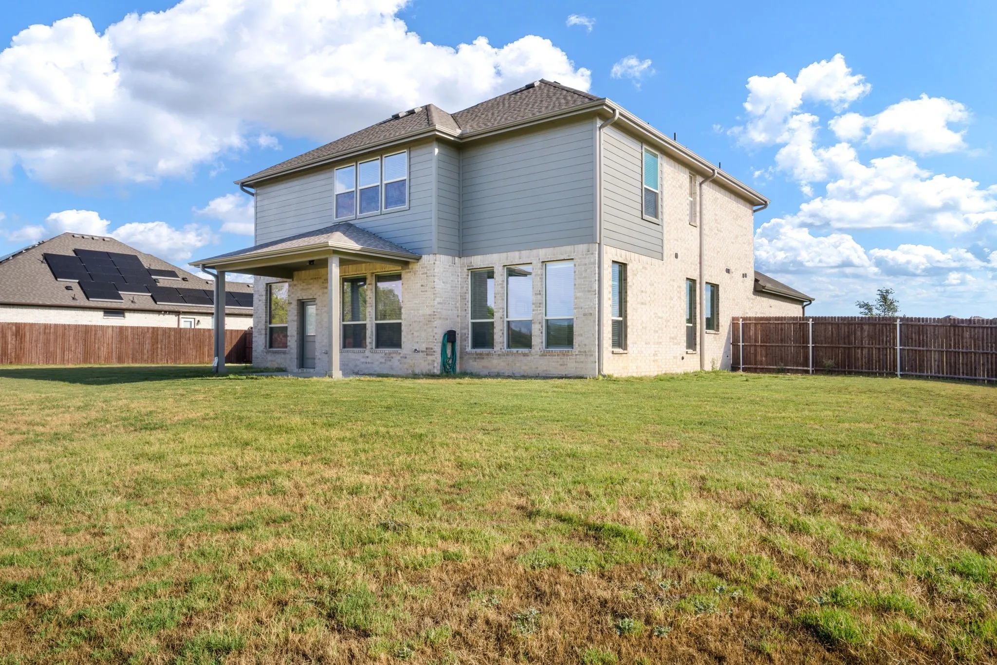 Two-story residence featuring light-colored brick and horizontal siding