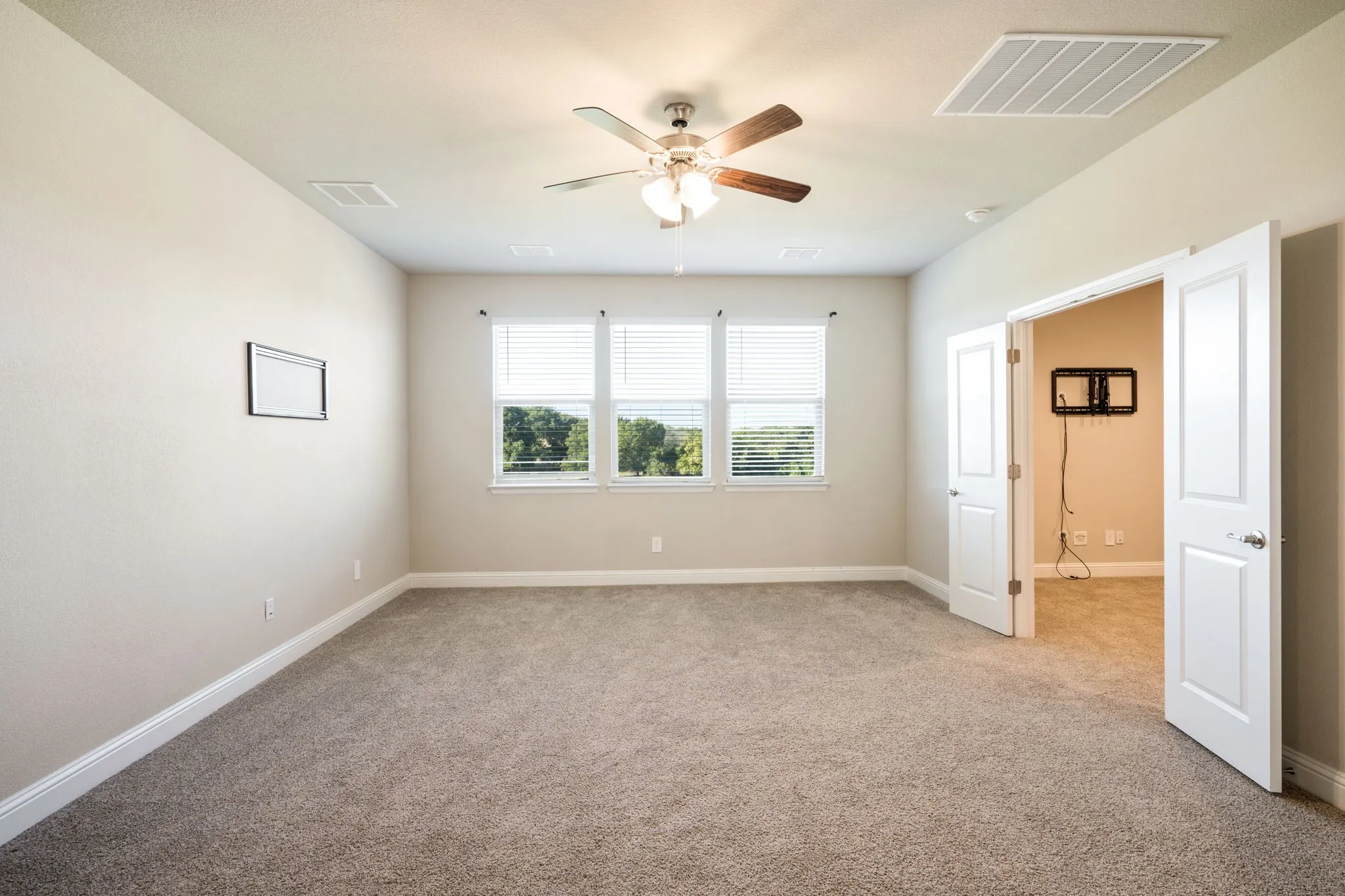 Neutral-toned carpeting, white trim, and a ceiling fan with integrated lighting