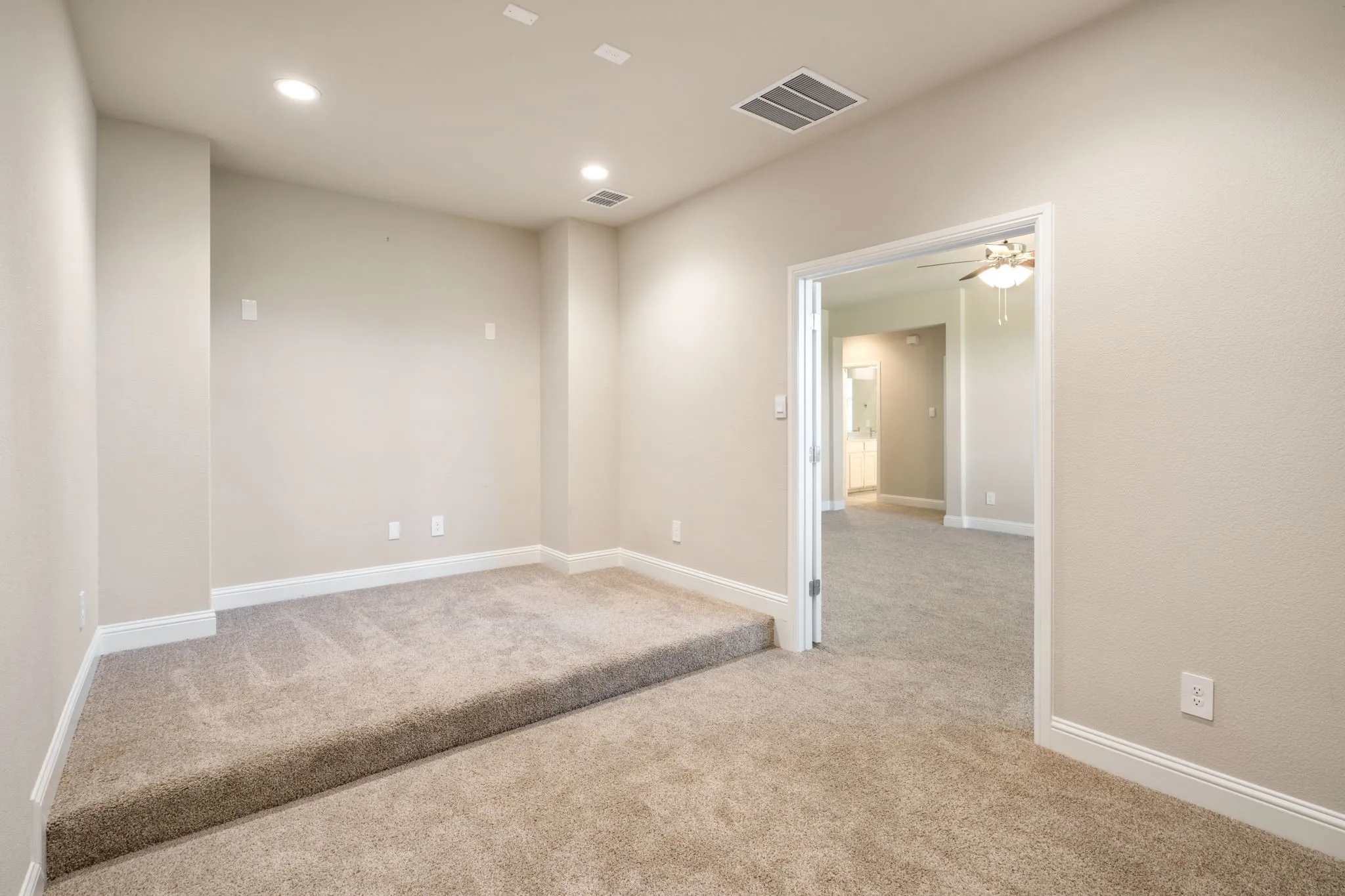 Raised carpeted platform, recessed lighting, neutral wall paint, carpeted flooring, and white trim