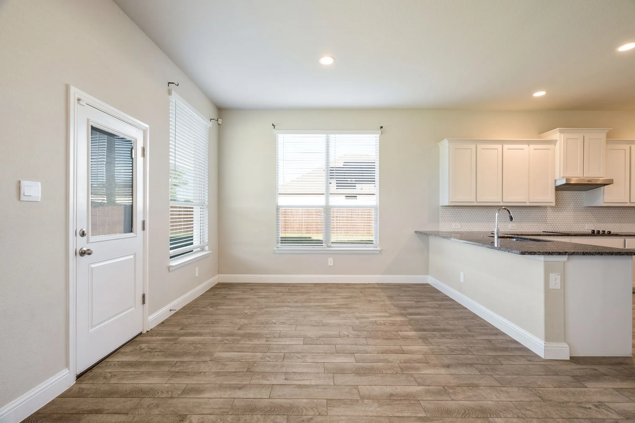 Open-concept living space featuring wood-finish flooring, recessed lighting, and ample natural light from multiple windows