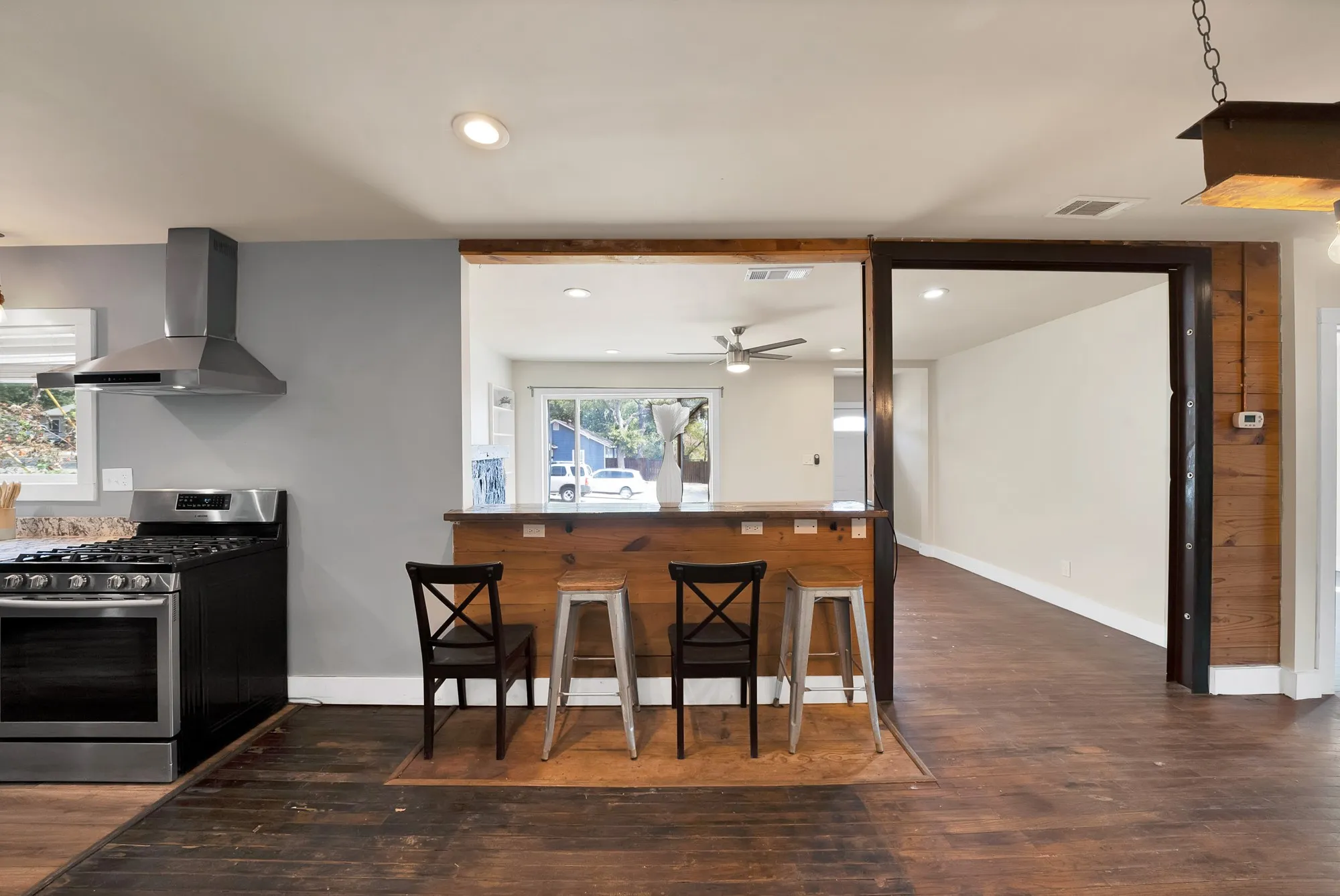 Breakfast bar: Knotty pine plank breakfast bar with built-in electrical outlets and pass-through to the living room. Stainless steel gas range and chimney vent hood, recessed lighting, and hardwood floors.