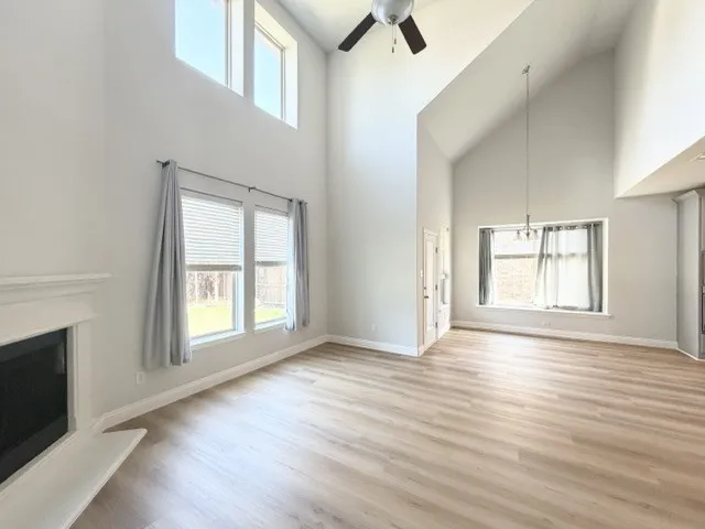 Vaulted ceilings with an exposed beam, wood-finish flooring, and a fireplace with a mantel