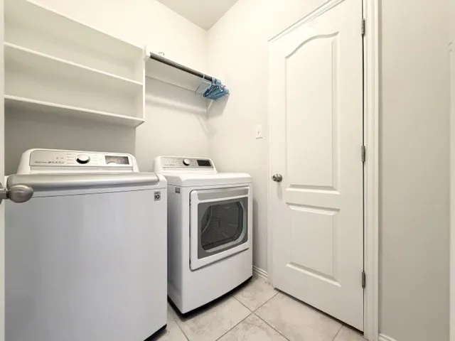 Laundry area featuring tile flooring, built-in shelving, and a garment rod