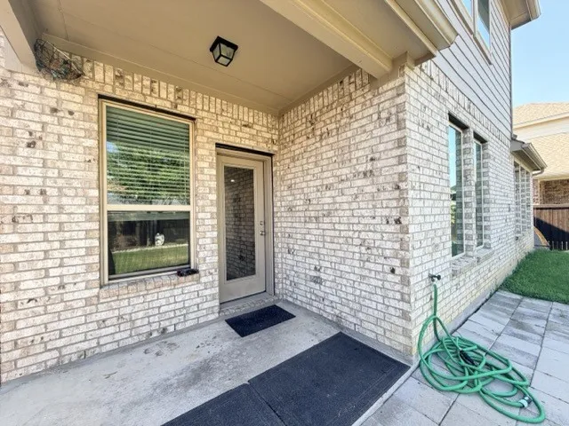 Covered patio with a concrete slab, light brick exterior, and multiple windows