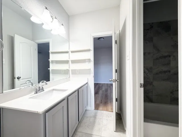 Dual sink vanity with white countertop, chrome fixtures, and grey cabinetry