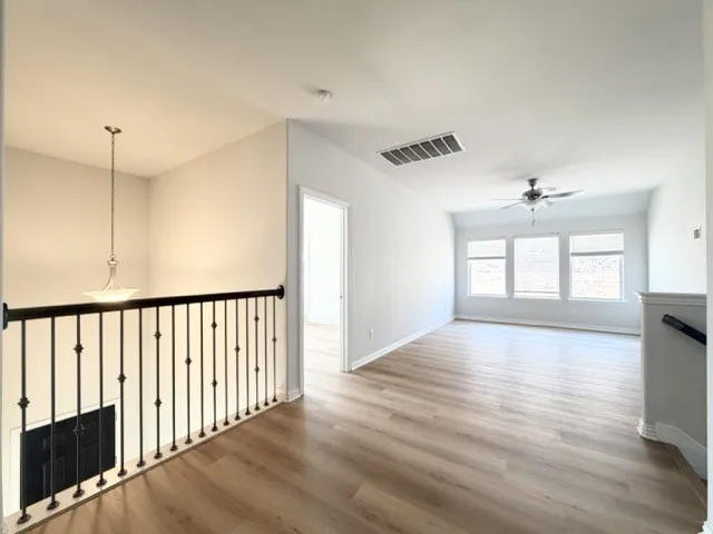 Spacious upper-level landing featuring wood-finish flooring, a contemporary ceiling fan, and multiple windows