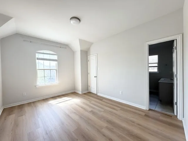Wood-finish flooring, a ceiling-mounted light fixture, and an arched window