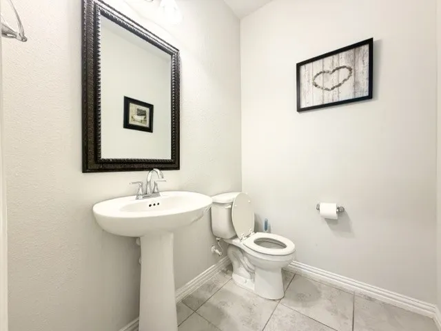 Pedestal sink with chrome faucet, framed mirror, and tiled flooring