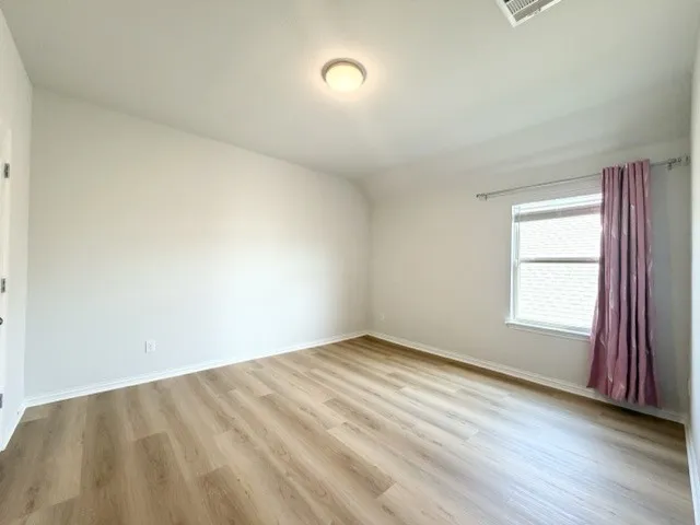Light wood-finish flooring, white walls, and a ceiling-mounted light fixture