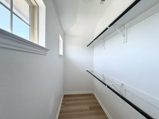 Wood-finish flooring, white walls, and built-in closet rods with shelving