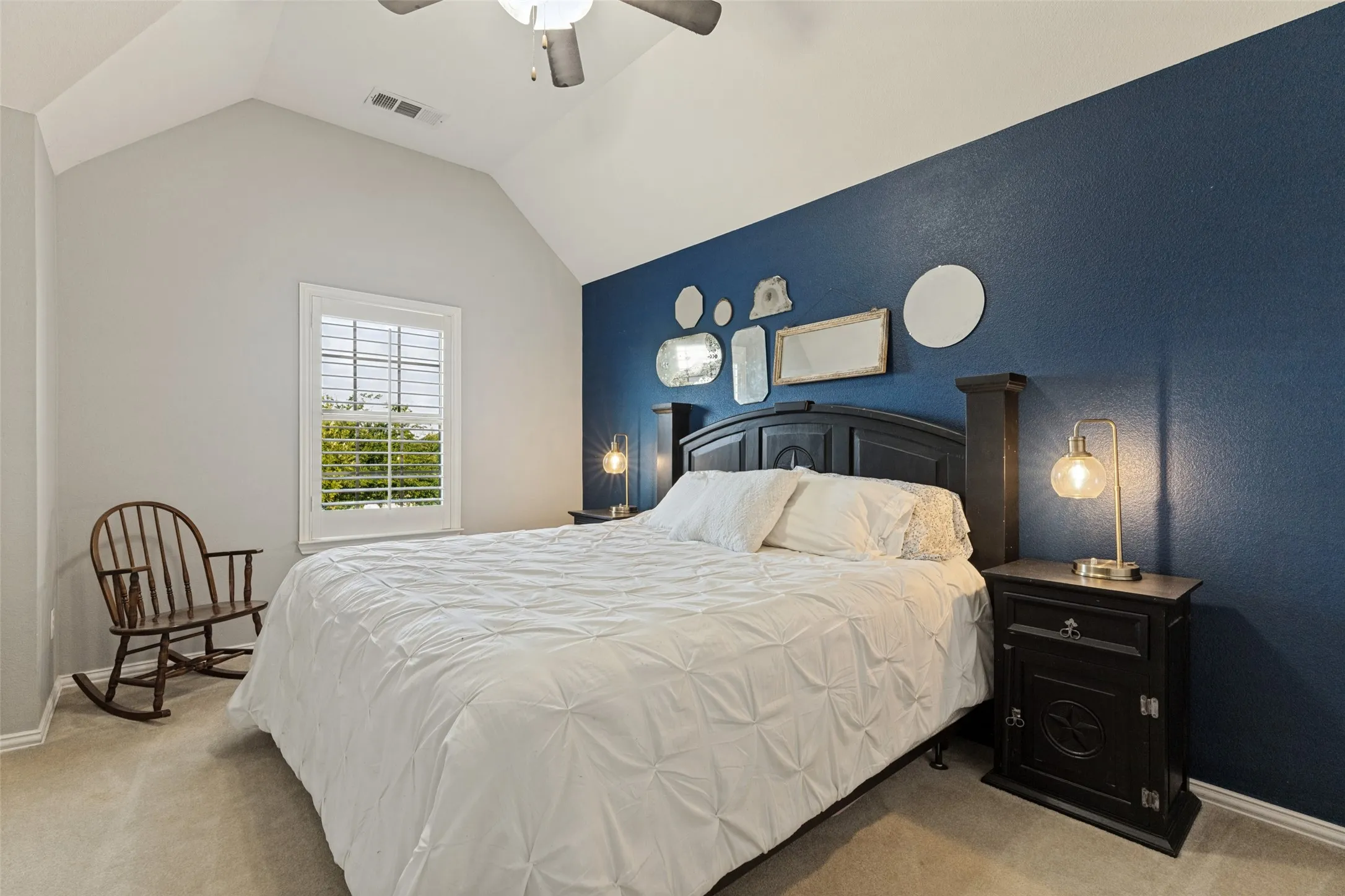 Bedroom with ceiling fan, window and beige carpet.